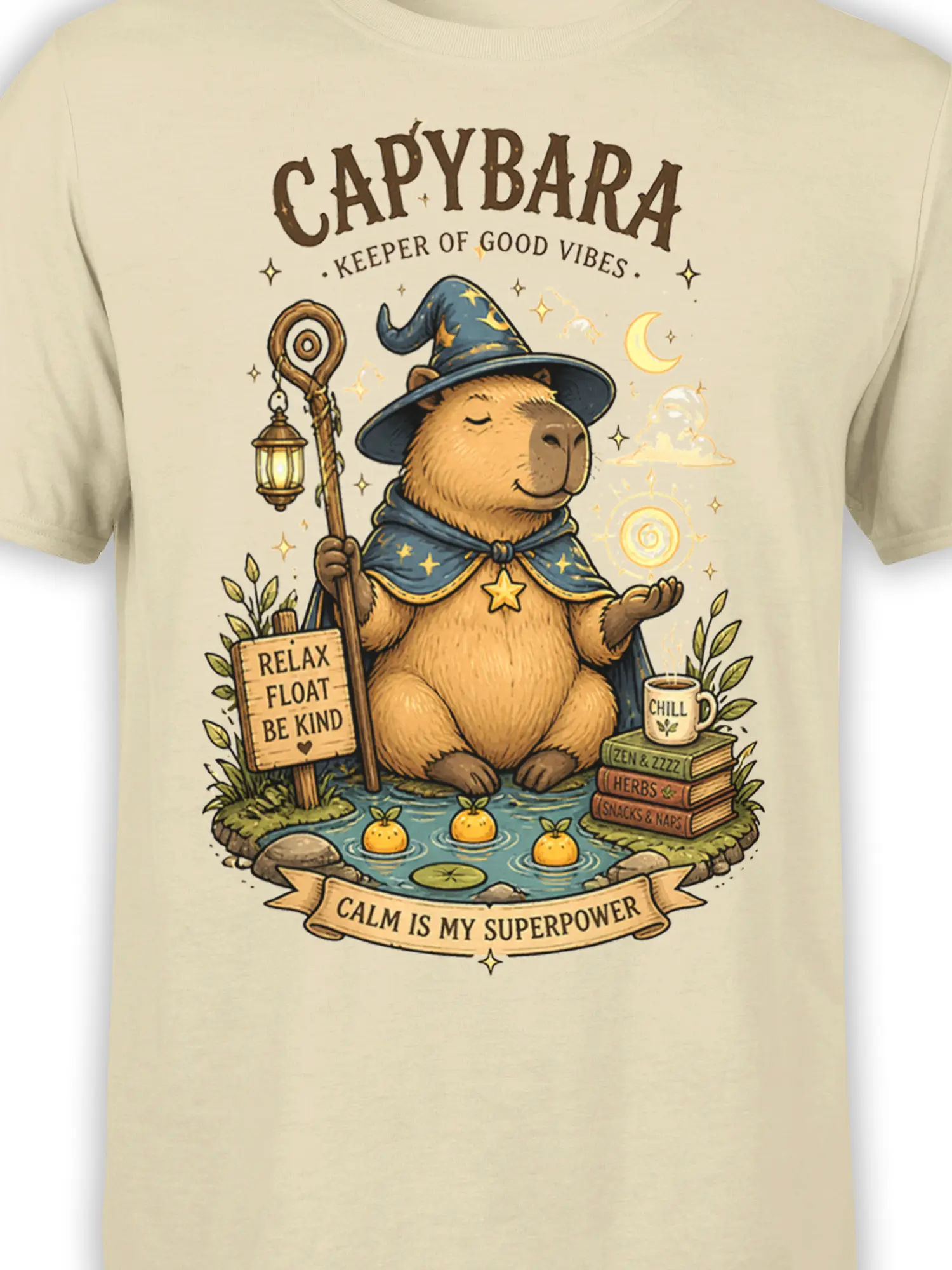 Close-up of wizard capybara artwork on a beige shirt with stars, a lantern, magical orb, and pond details