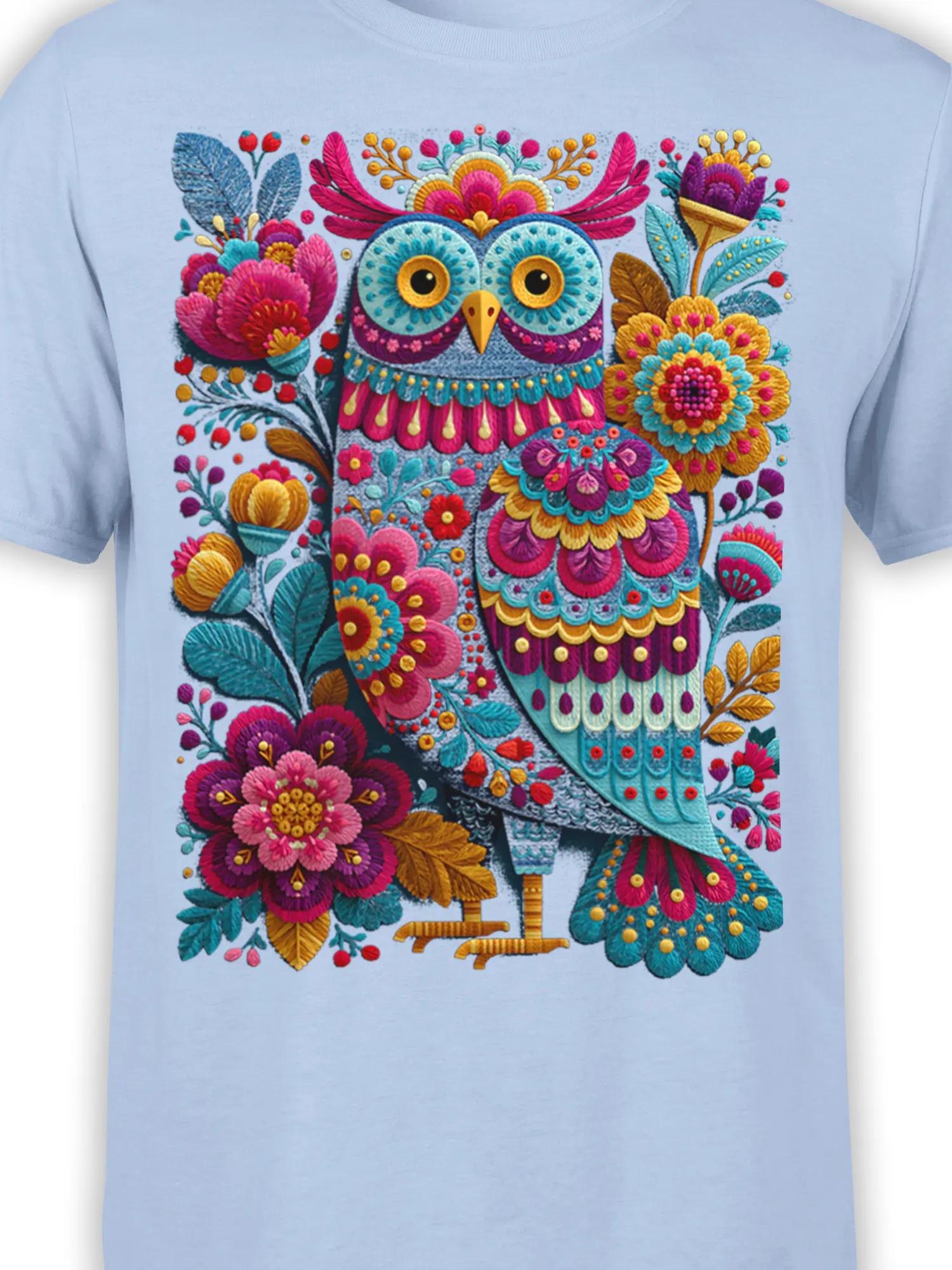 Close-up of the colorful owl and floral folk-art design on a light blue shirt