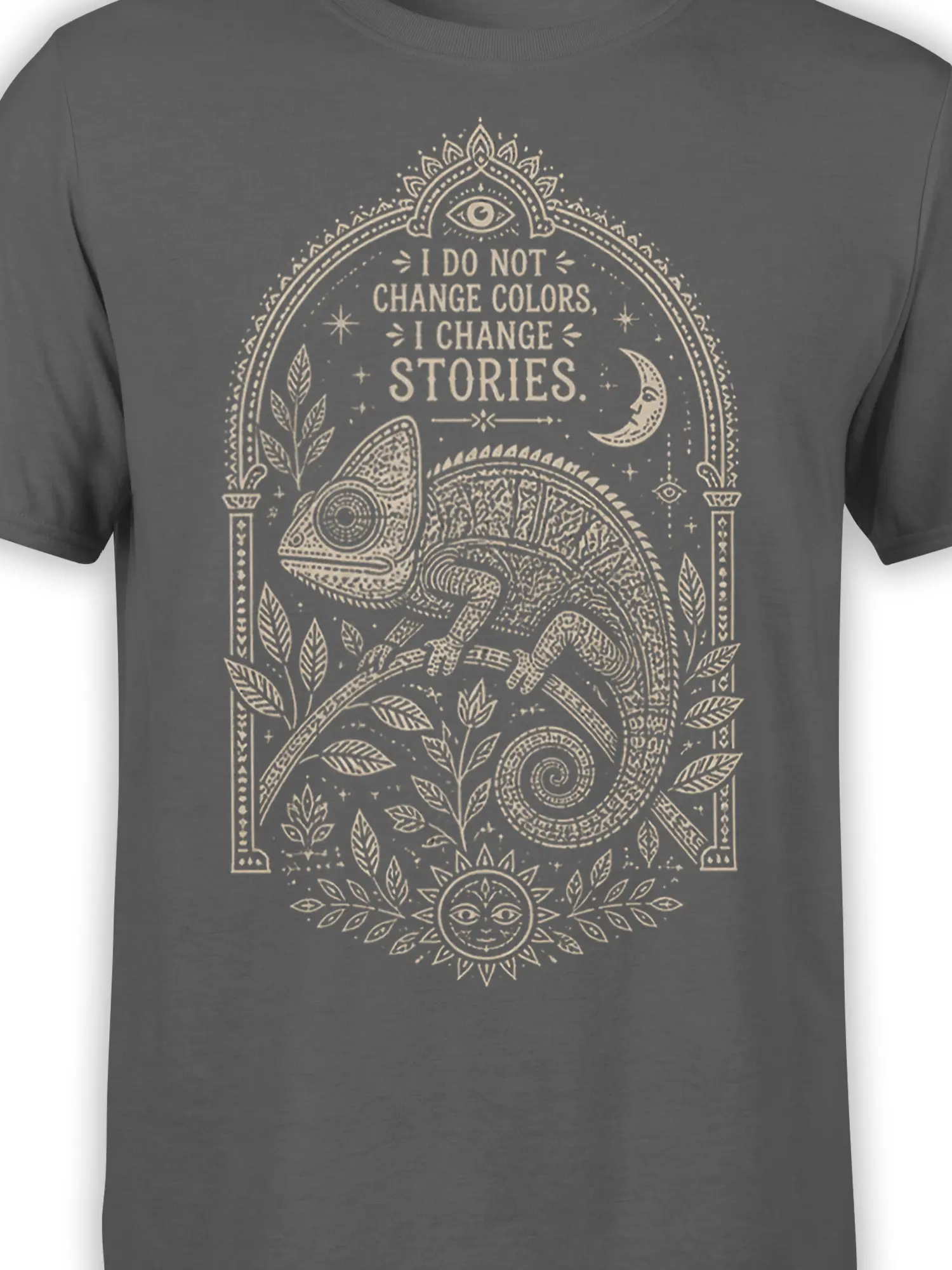 Close-up of ornate chameleon artwork with moon, sun face, eye symbols, leaves, and text on a gray T-shirt