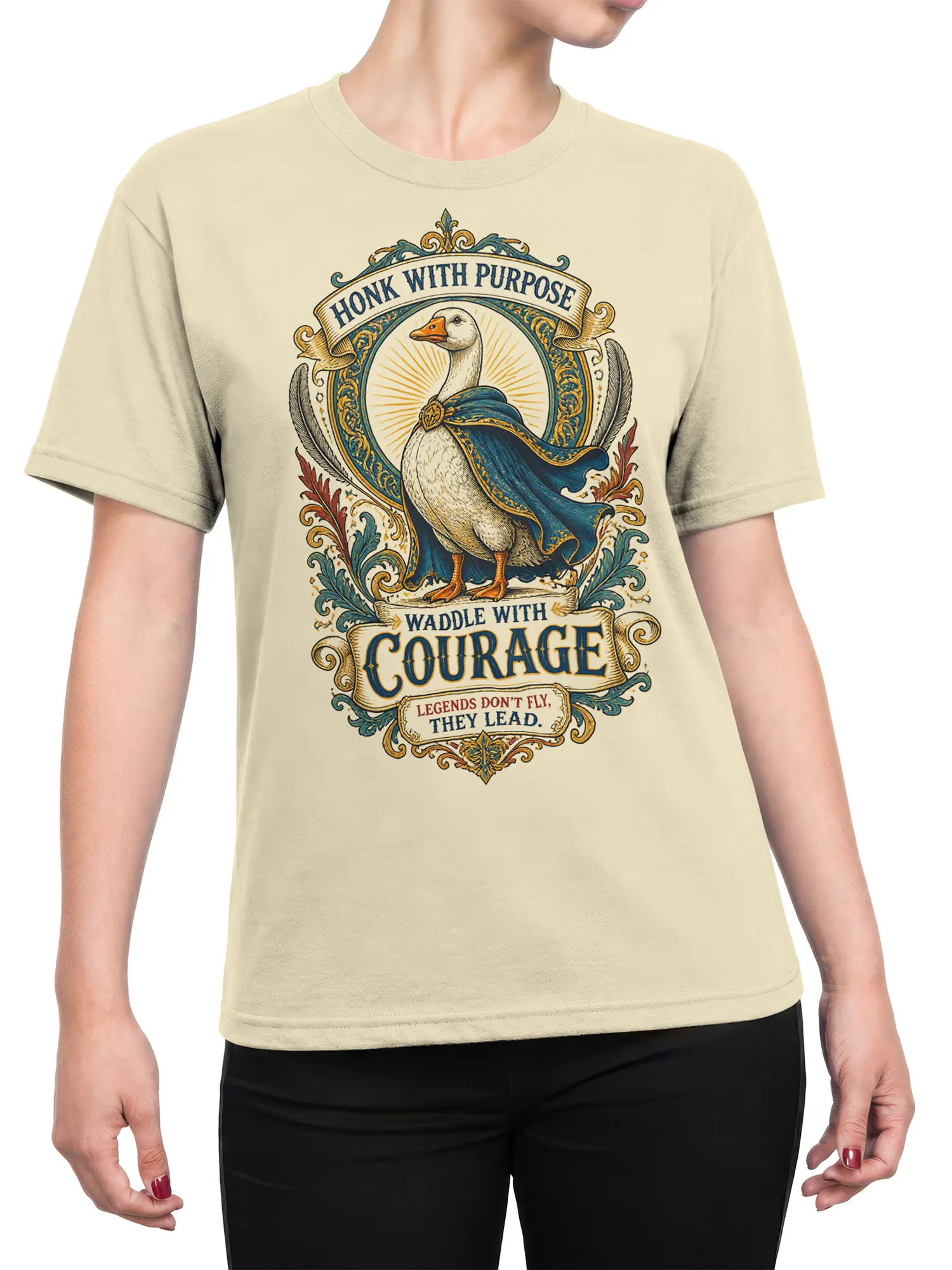 Female torso wearing a beige goose T-shirt with a blue-caped bird, ornate crest, and vintage courage message