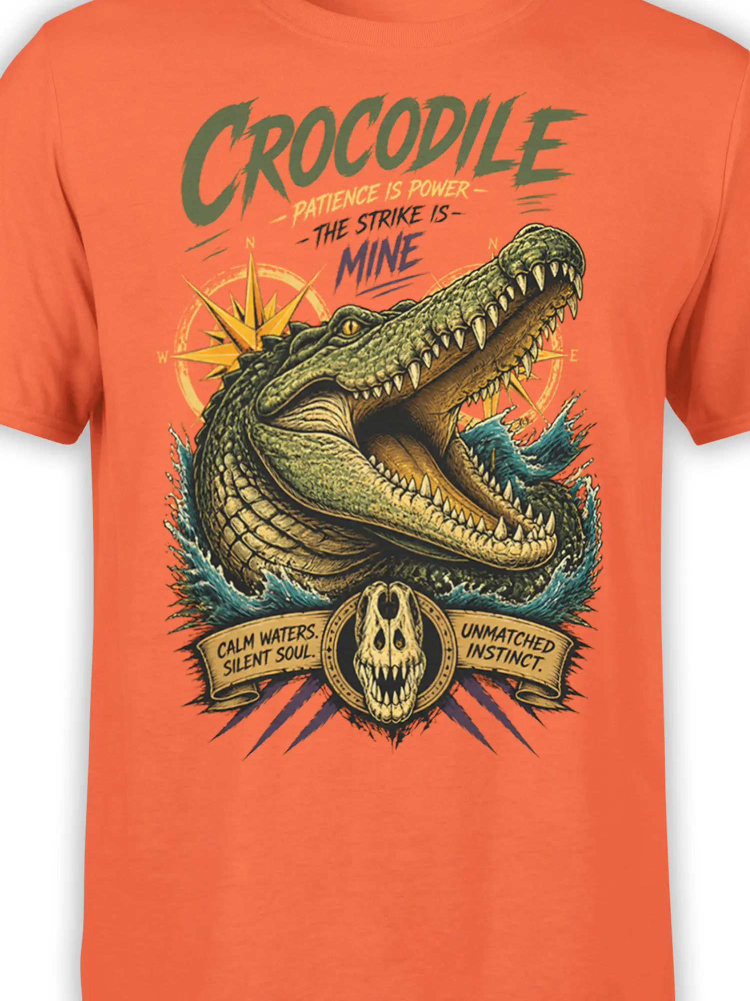 Close-up of crocodile graphic on orange shirt with sharp teeth, compass details, blue water, and vintage lettering