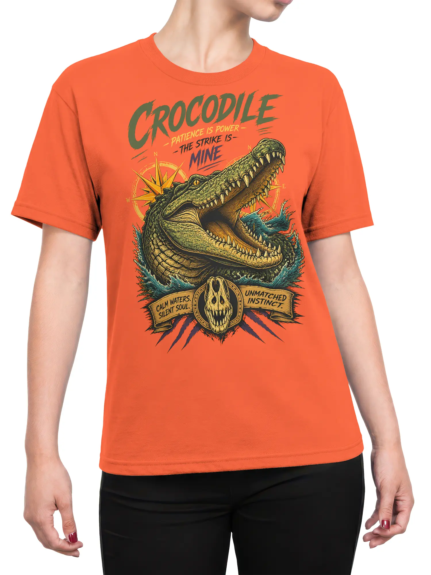Female torso wearing an orange crocodile T-shirt with bold vintage artwork, open jaws, compass, and water details