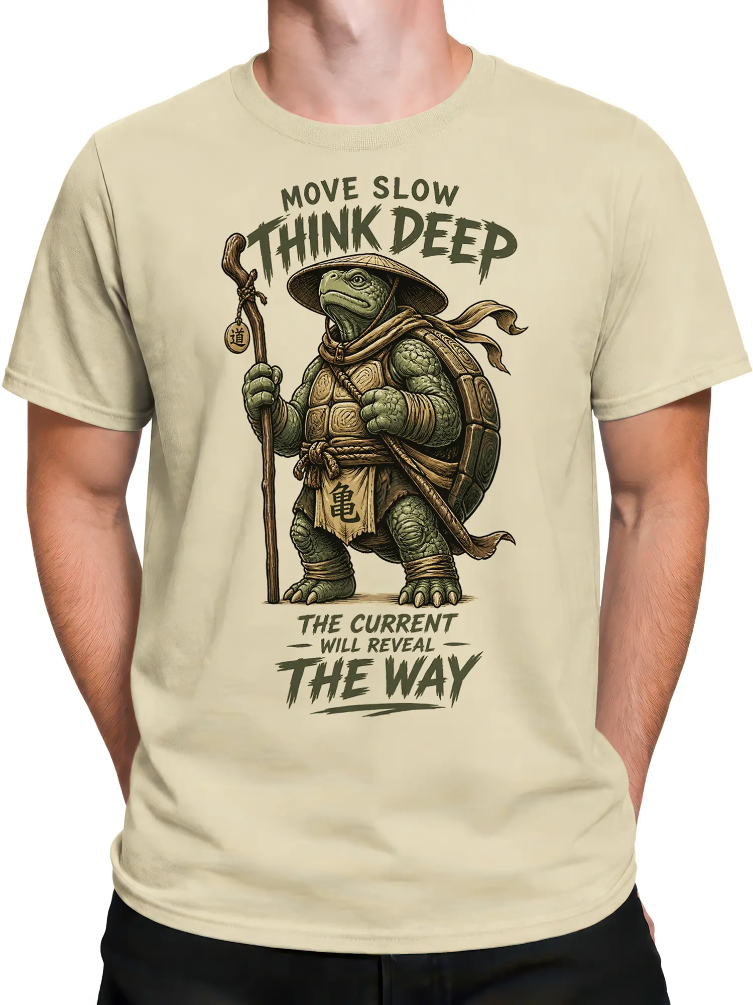 Male torso wearing a beige turtle graphic T-shirt with a staff, shell armor, and thoughtful text