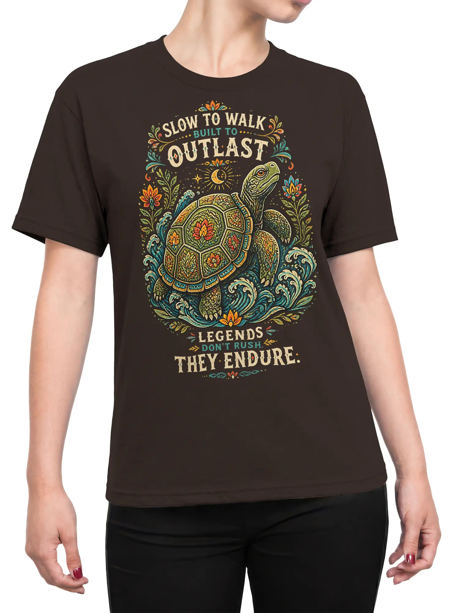 Female torso wearing a brown turtle T-shirt with colorful floral artwork, ocean waves, moon, and a slow-living message