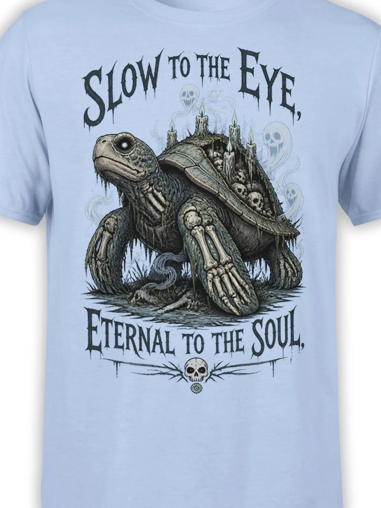 Close-up of haunted turtle artwork with candlelit shell, skulls, bones, and gothic text on light blue fabric