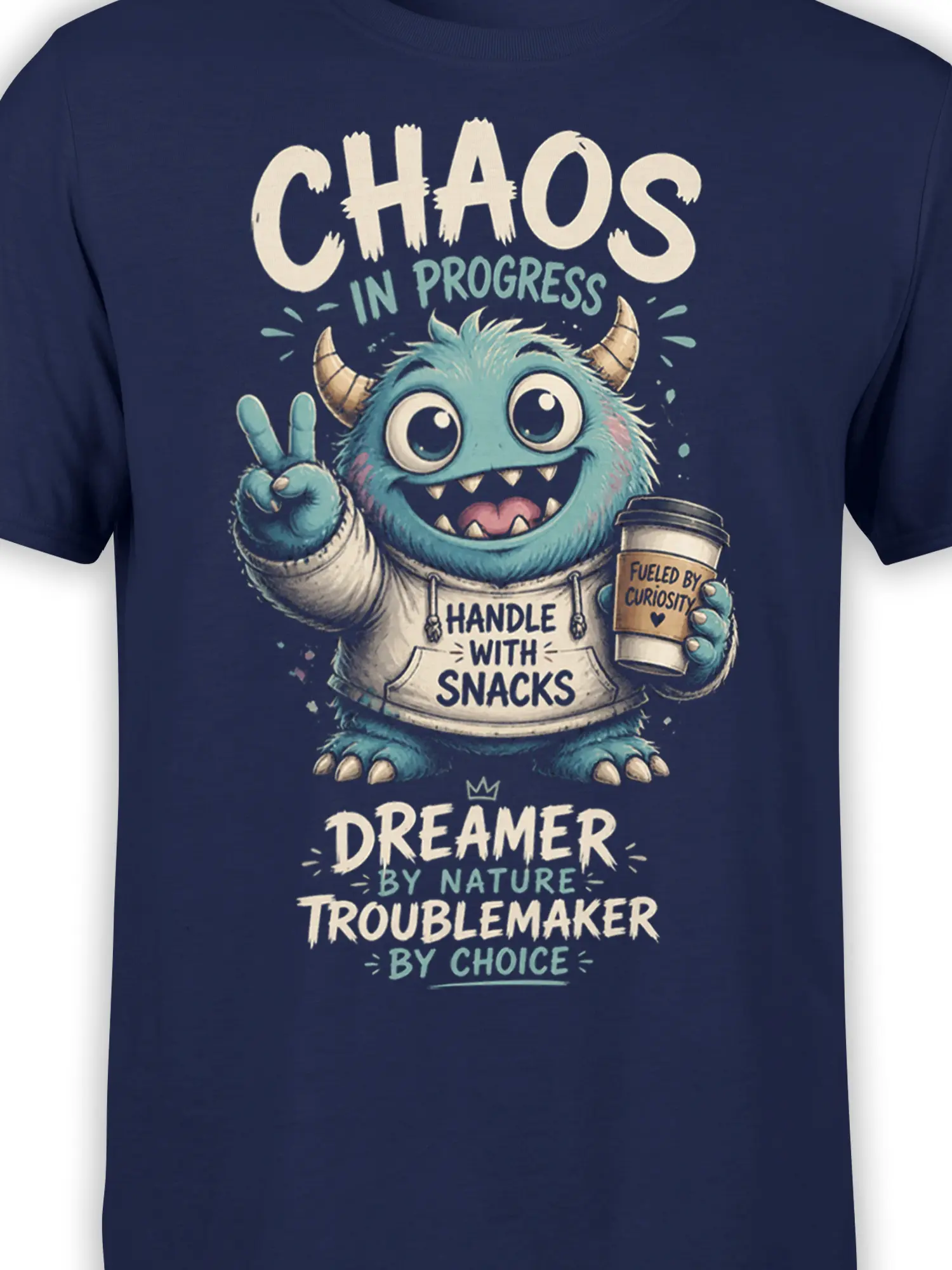 Close-up of blue fuzzy monster artwork, coffee cup, horns, and Handle With Snacks text on a navy T-shirt