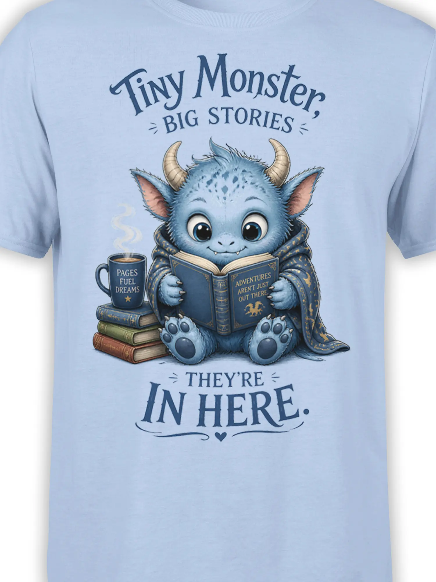 Close-up of blue horned reading monster artwork and storybook text on a light blue T-shirt