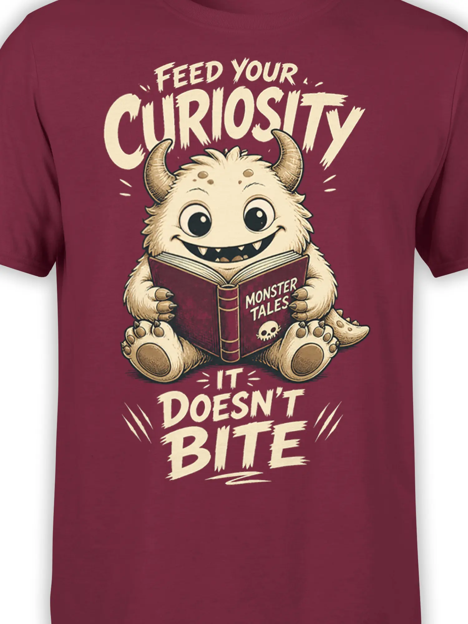 Close-up of horned monster, open book, claws, and cream lettering on a burgundy graphic T-shirt