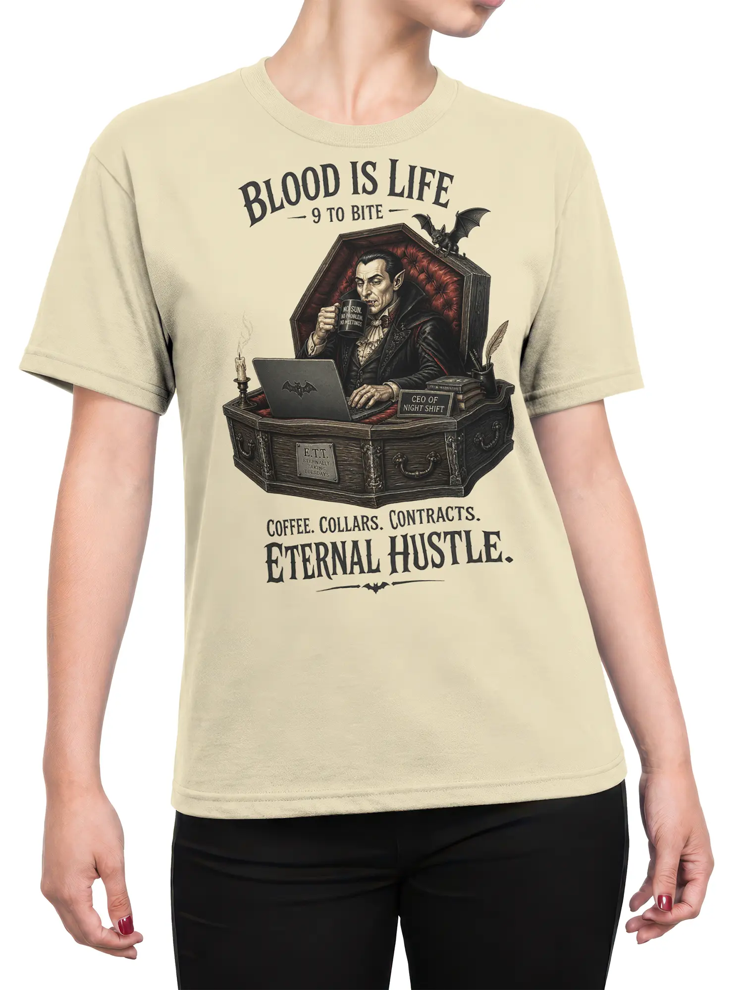 Female torso wearing a beige vampire T-shirt with night shift lettering and a detailed gothic coffin office design