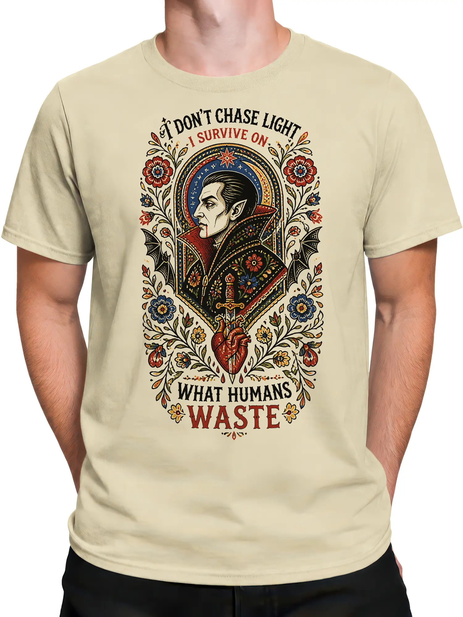 Male torso wearing a beige vampire graphic T-shirt with ornate flowers, bats, sword, heart, and gothic lettering