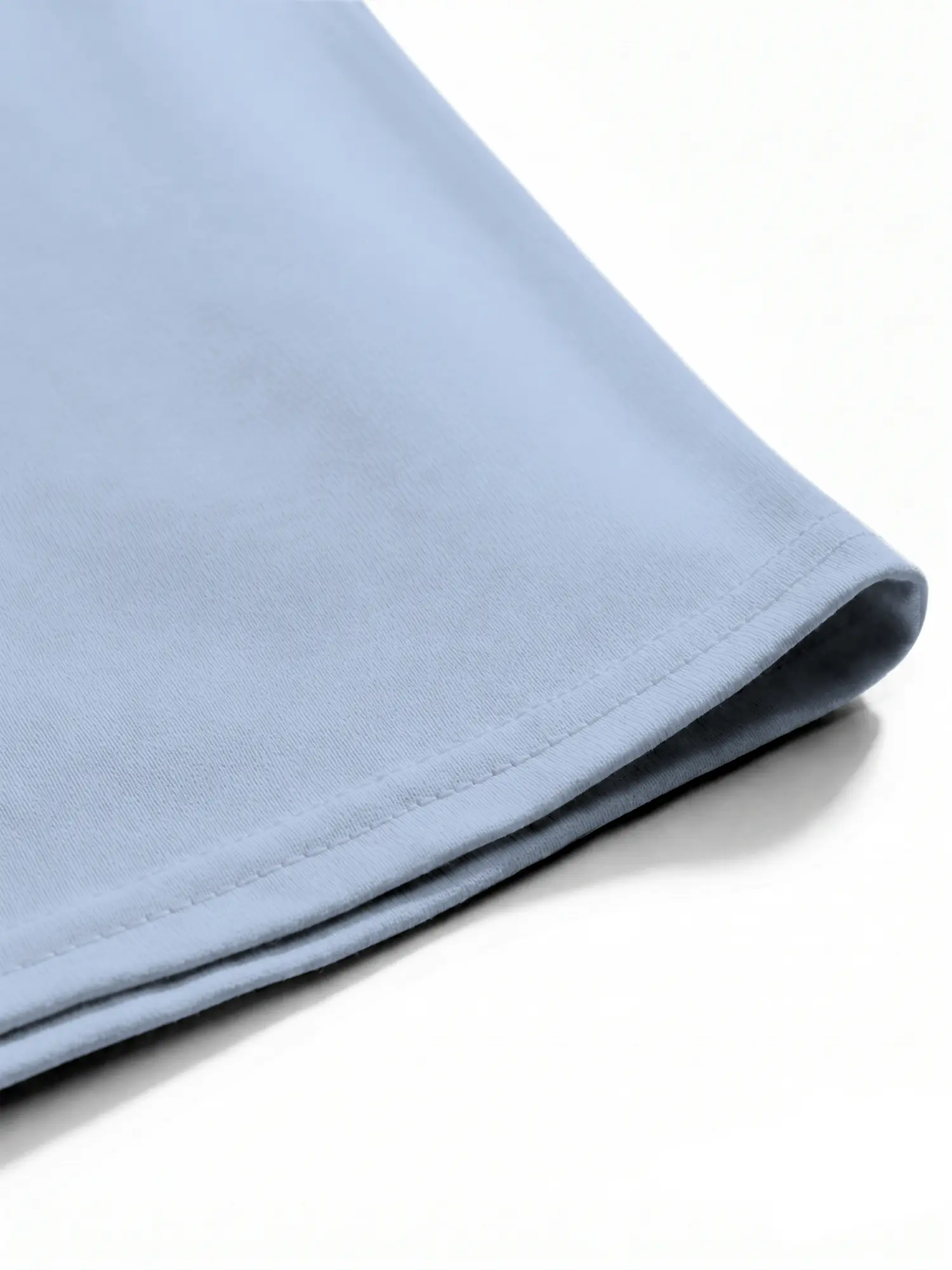 Light blue cotton T-shirt hem showing neat stitching and smooth fabric texture
