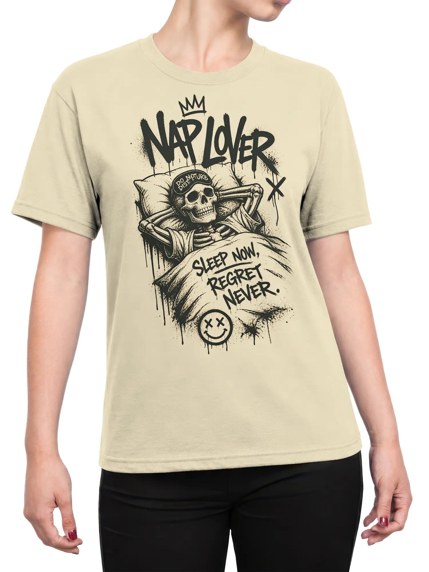 Female torso wearing a beige T-shirt with a crowned sleeping skeleton and “Sleep Now, Regret Never” design