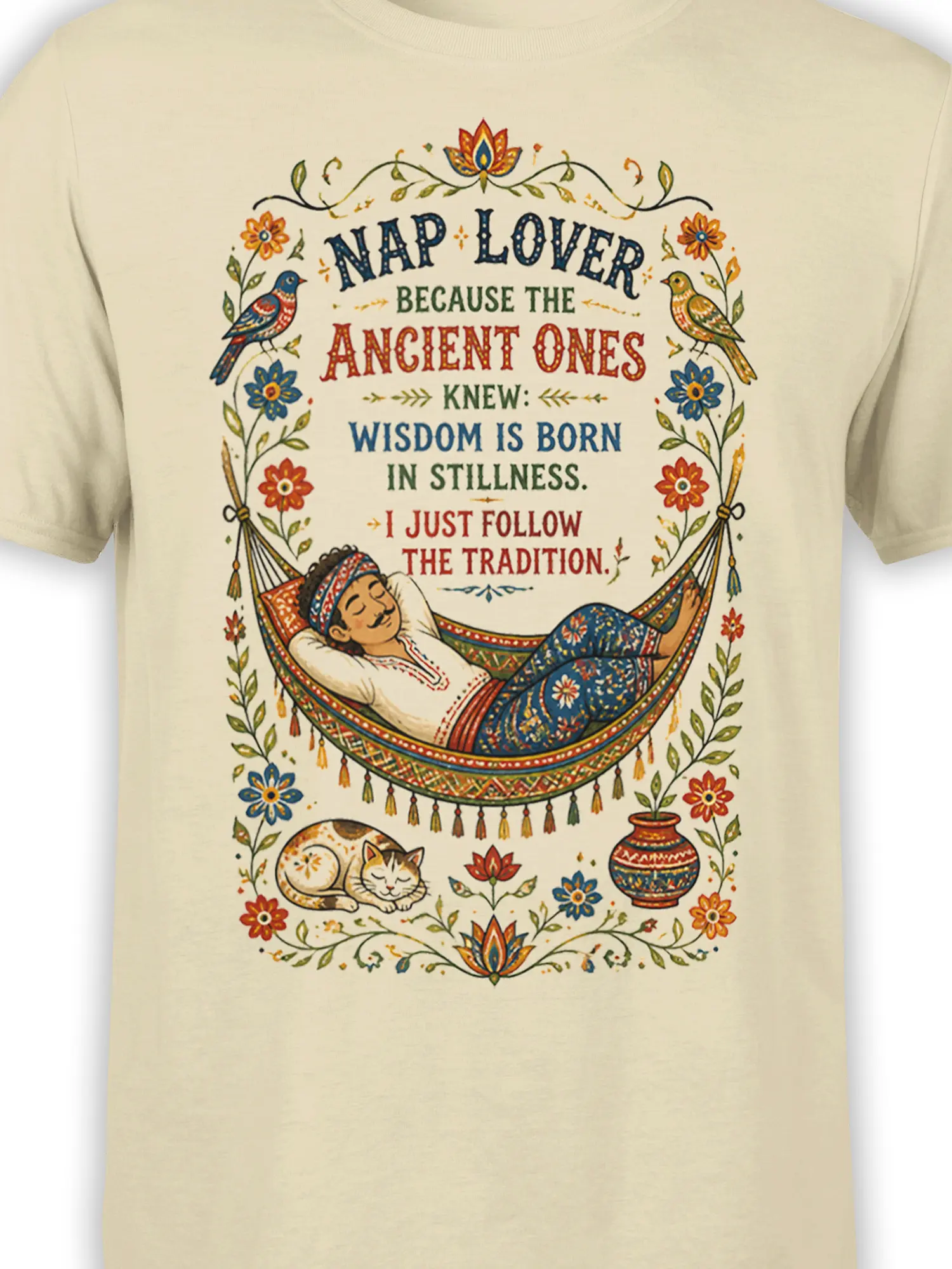 Close-up of the beige cat T-shirt design showing the hammock nap scene, floral border, birds, cat, and colorful ornamental details
