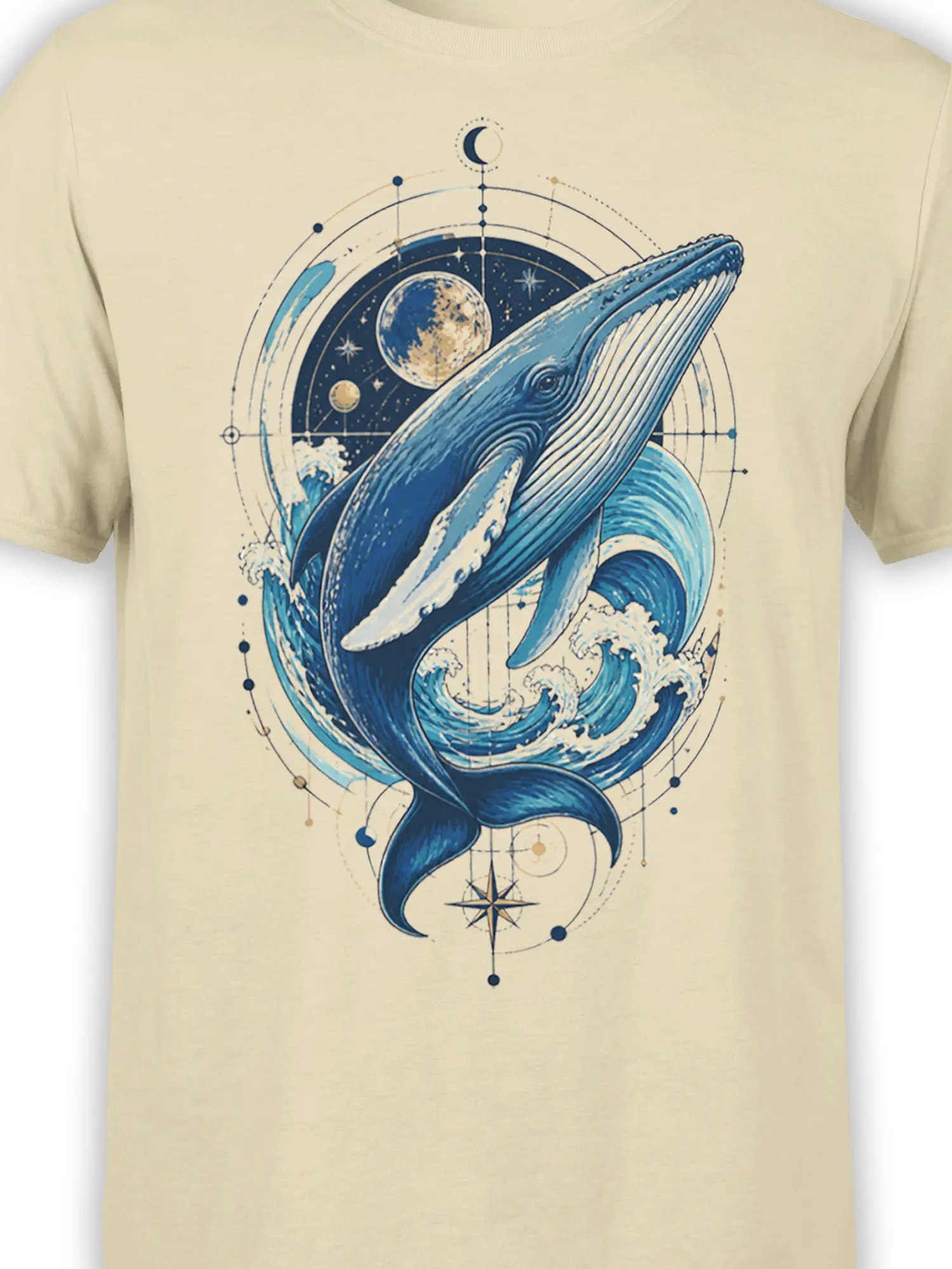 Close-up of blue whale artwork with waves, moon, stars, planets, and compass details on a beige T-shirt