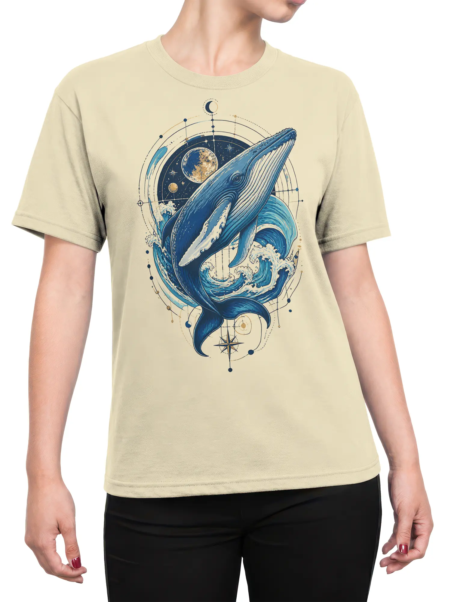 Female torso wearing a beige whale T-shirt with blue cosmic ocean artwork and moon, star, and compass details