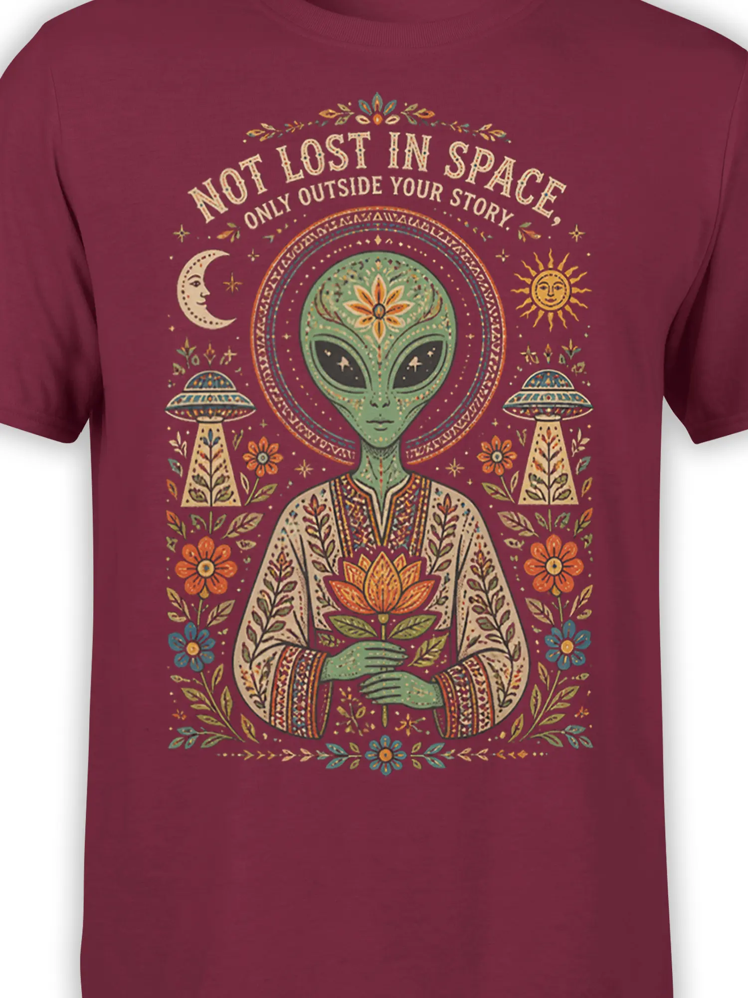 Close-up of maroon alien shirt design with a green alien, orange lotus, moon, sun, UFOs, and floral details