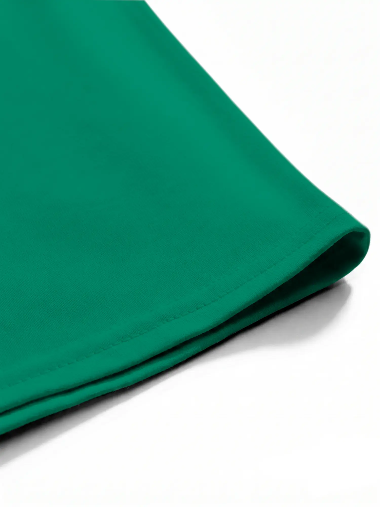Green cotton T-shirt hem and stitching shown in close-up with neat seam details and fabric texture