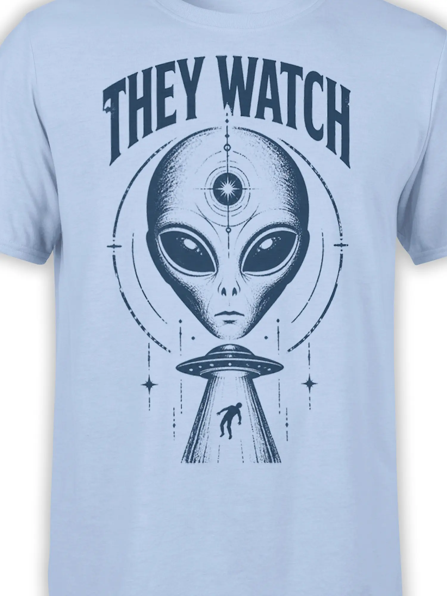 Close-up of the light blue alien graphic tee showing the extraterrestrial face, “THEY WATCH” text, and flying saucer design