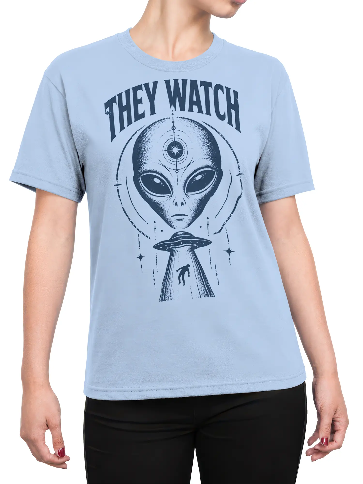 Female torso wearing a light blue alien T-shirt with a vintage extraterrestrial, UFO beam, stars, and “THEY WATCH” graphic