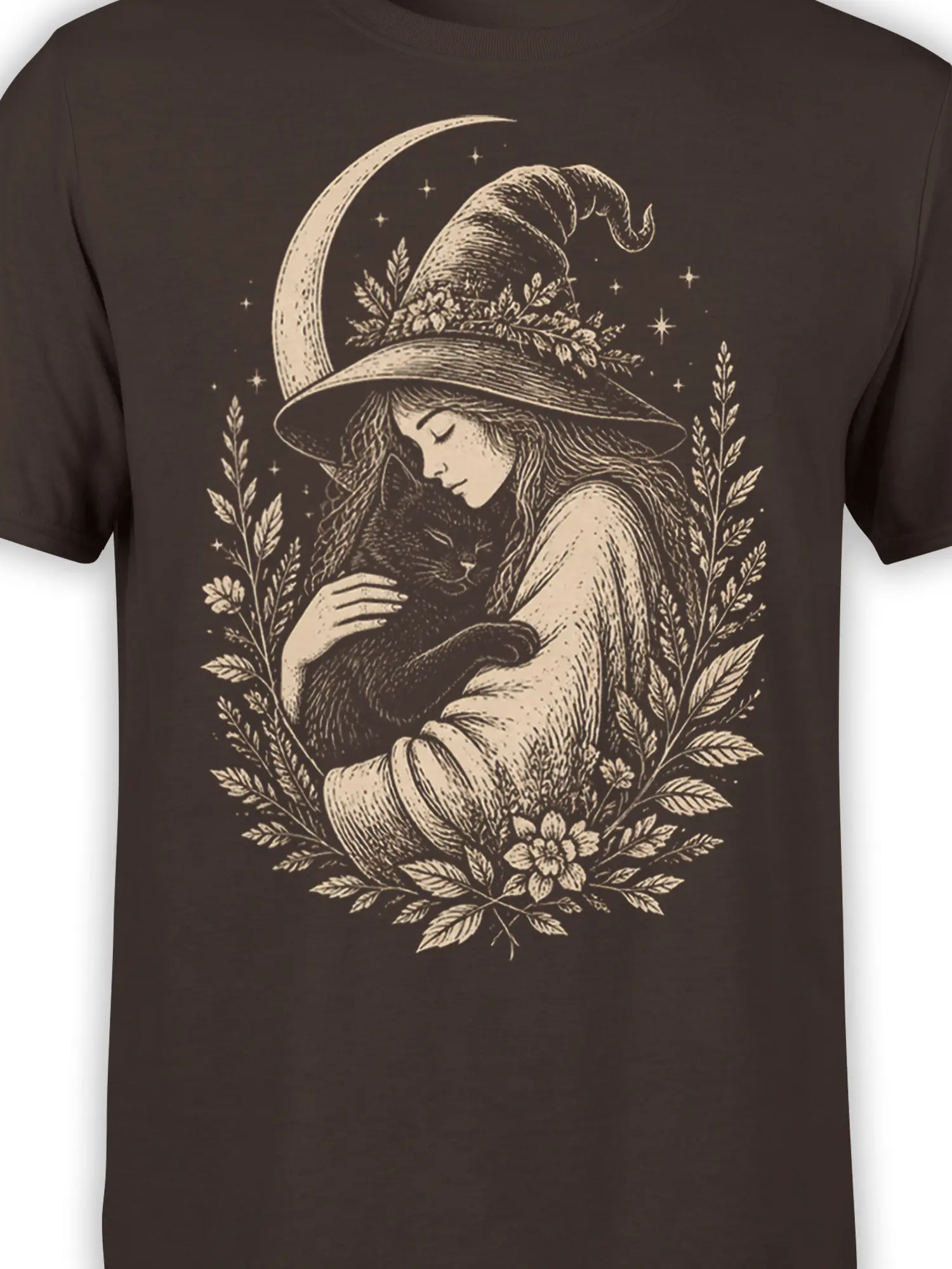Close-up of witch and black cat artwork with moon, stars, and flowers on a brown shirt