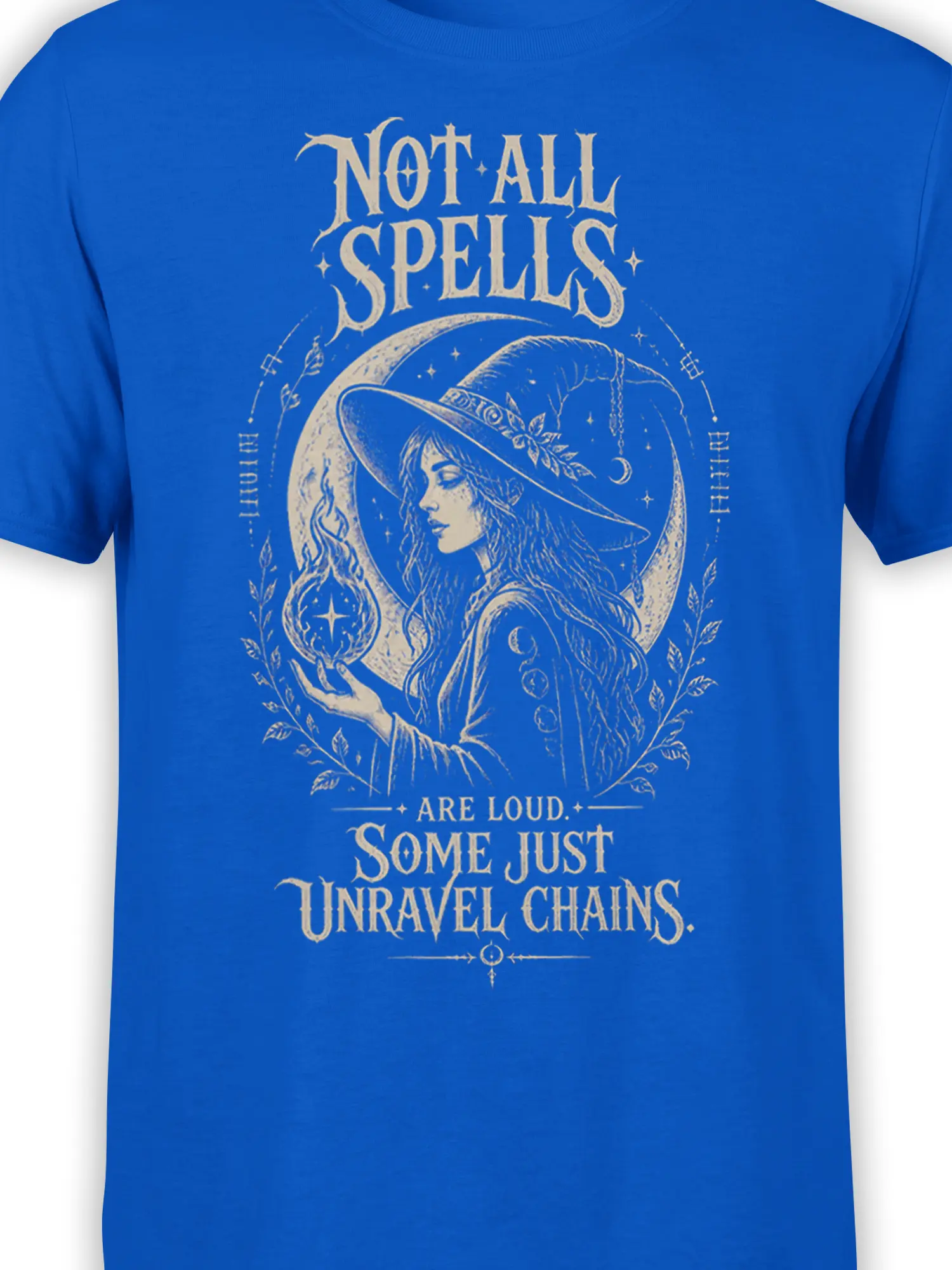 Close-up of mystical witch artwork, glowing flame, crescent moon, and cream lettering on a royal blue T-shirt