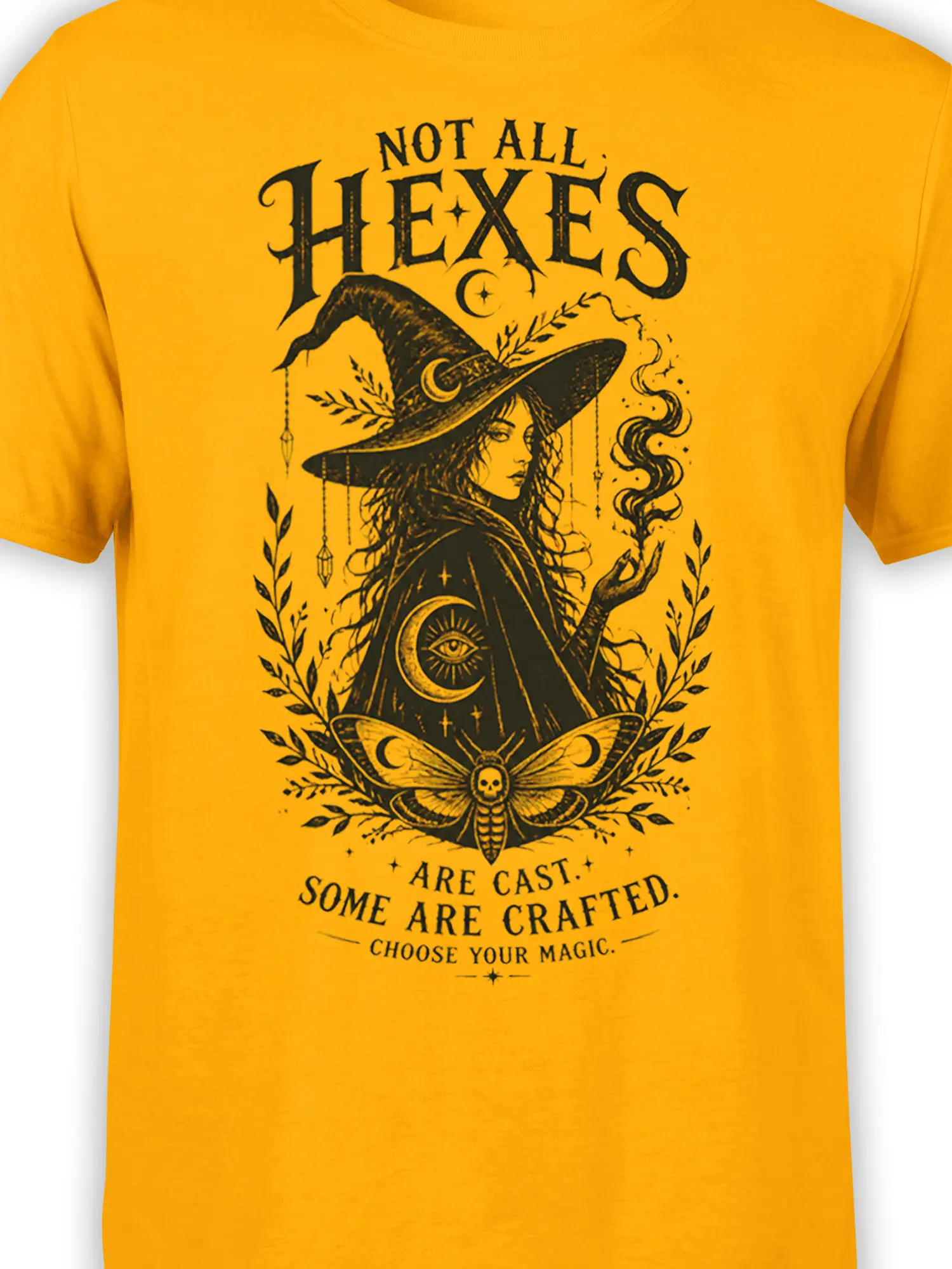 Close-up of yellow witch graphic tee showing the witch, crescent moon, eye symbol, smoke, and moth details