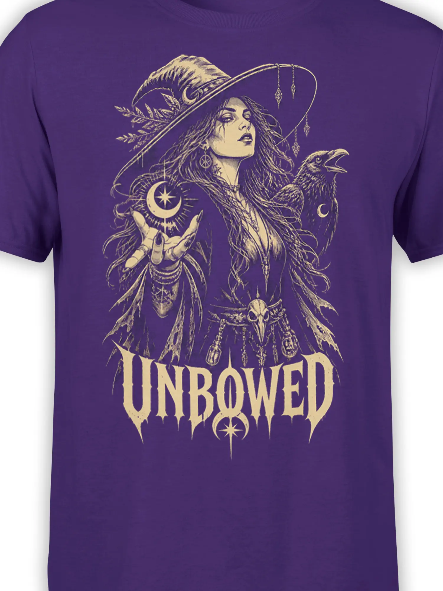 Close-up of purple T-shirt artwork with a witch, raven, crescent moon, star, and gothic UNBOWED text