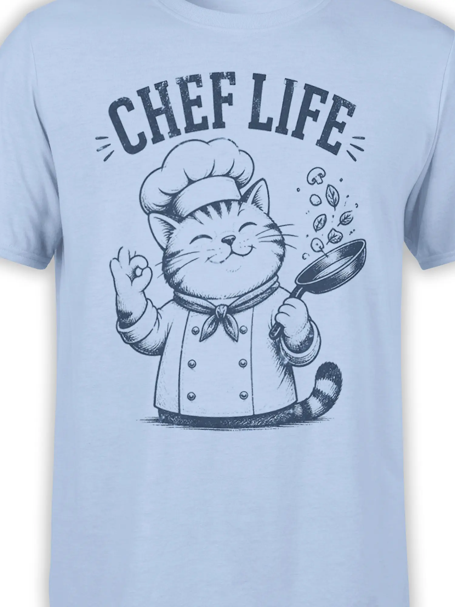 Close-up of the cat chef graphic and frying pan printed on a light blue T-shirt