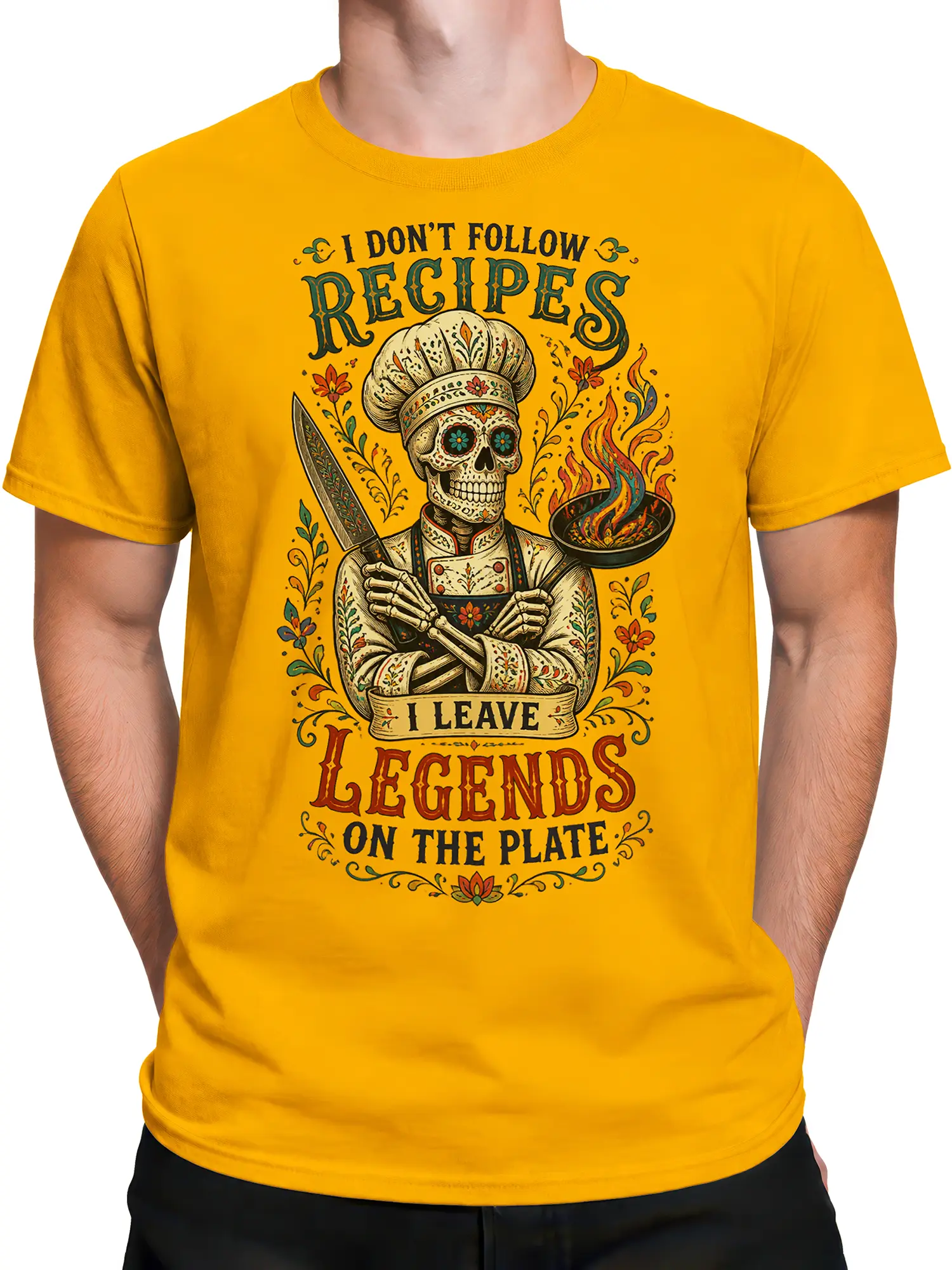 Male torso wearing a yellow T-shirt with skeleton chef, kitchen knife, flaming pan, and floral artwork