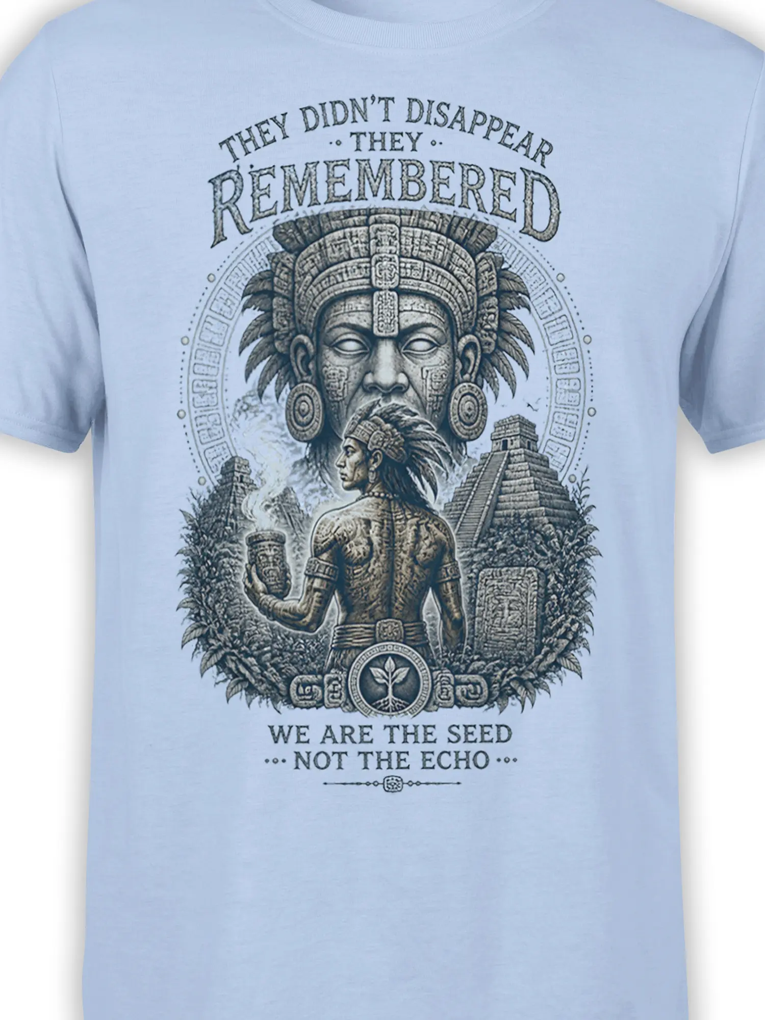 Close-up of indigenous warrior artwork, carved symbols, temples, and text on a light blue T-shirt