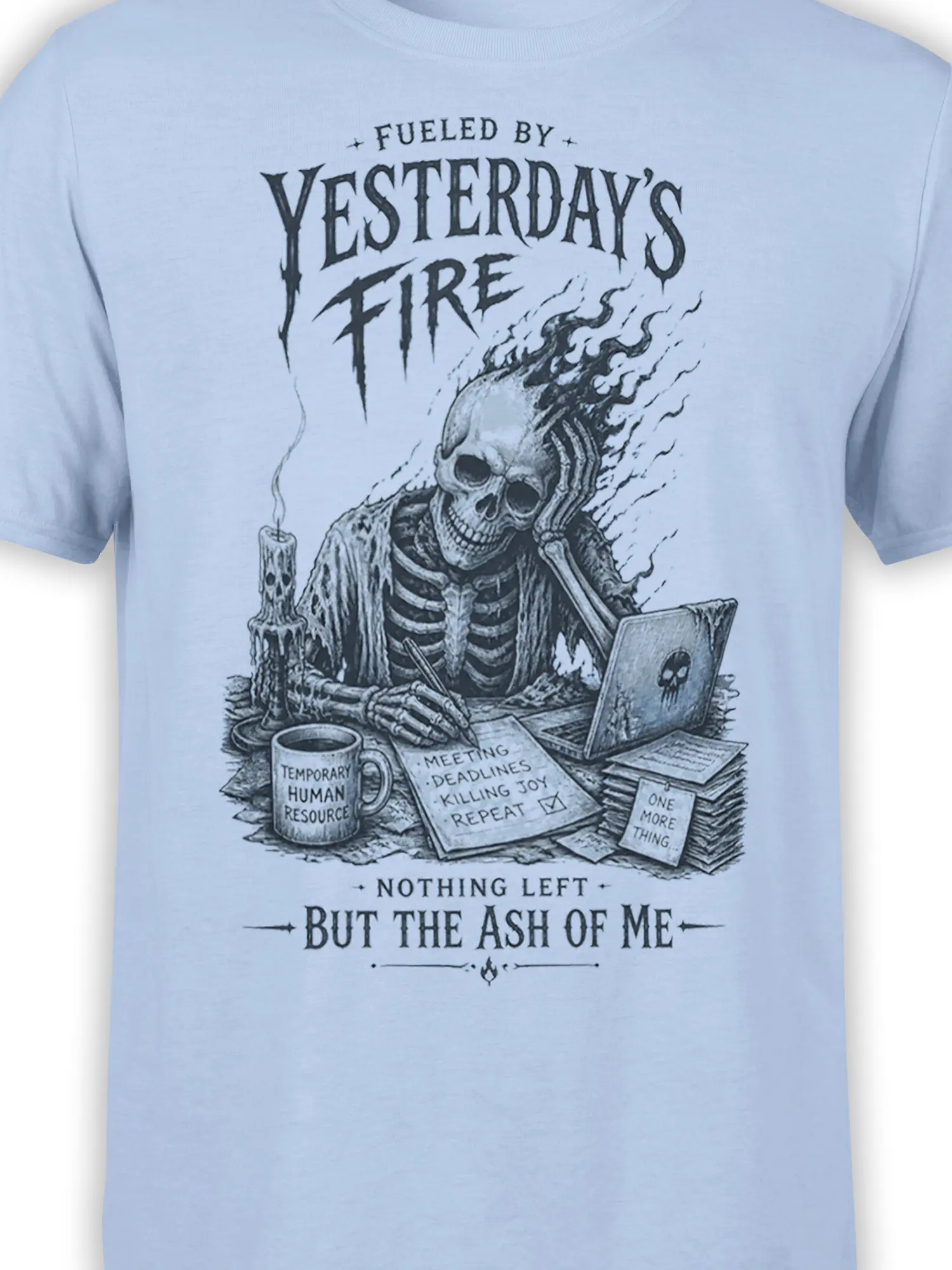 Close-up of office skeleton skull graphic with laptop, candle, deadlines, and burnout text on light blue fabric