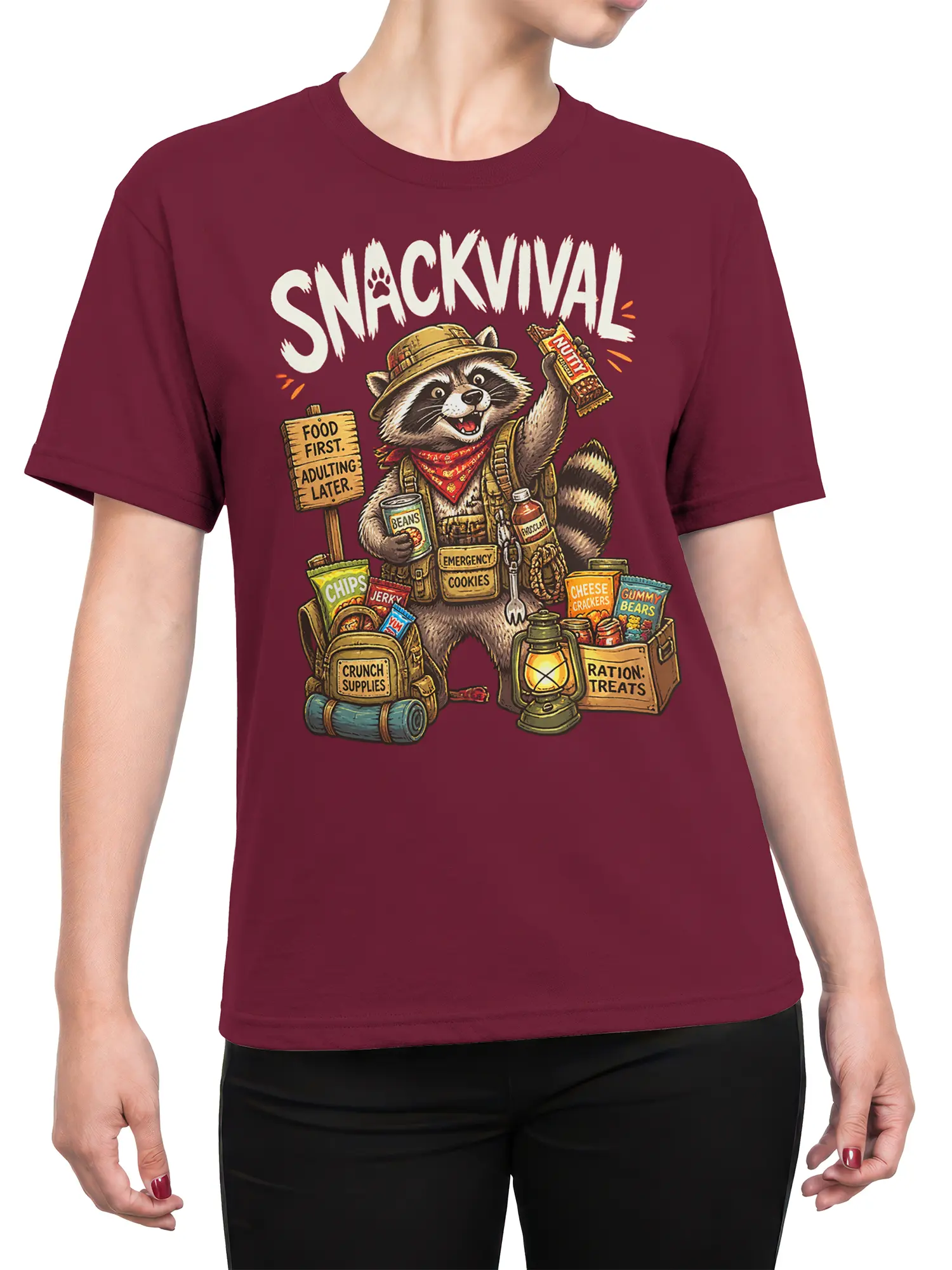 Female torso wearing a burgundy T-shirt with a detailed raccoon snack survival illustration and bold “SNACKVIVAL” text