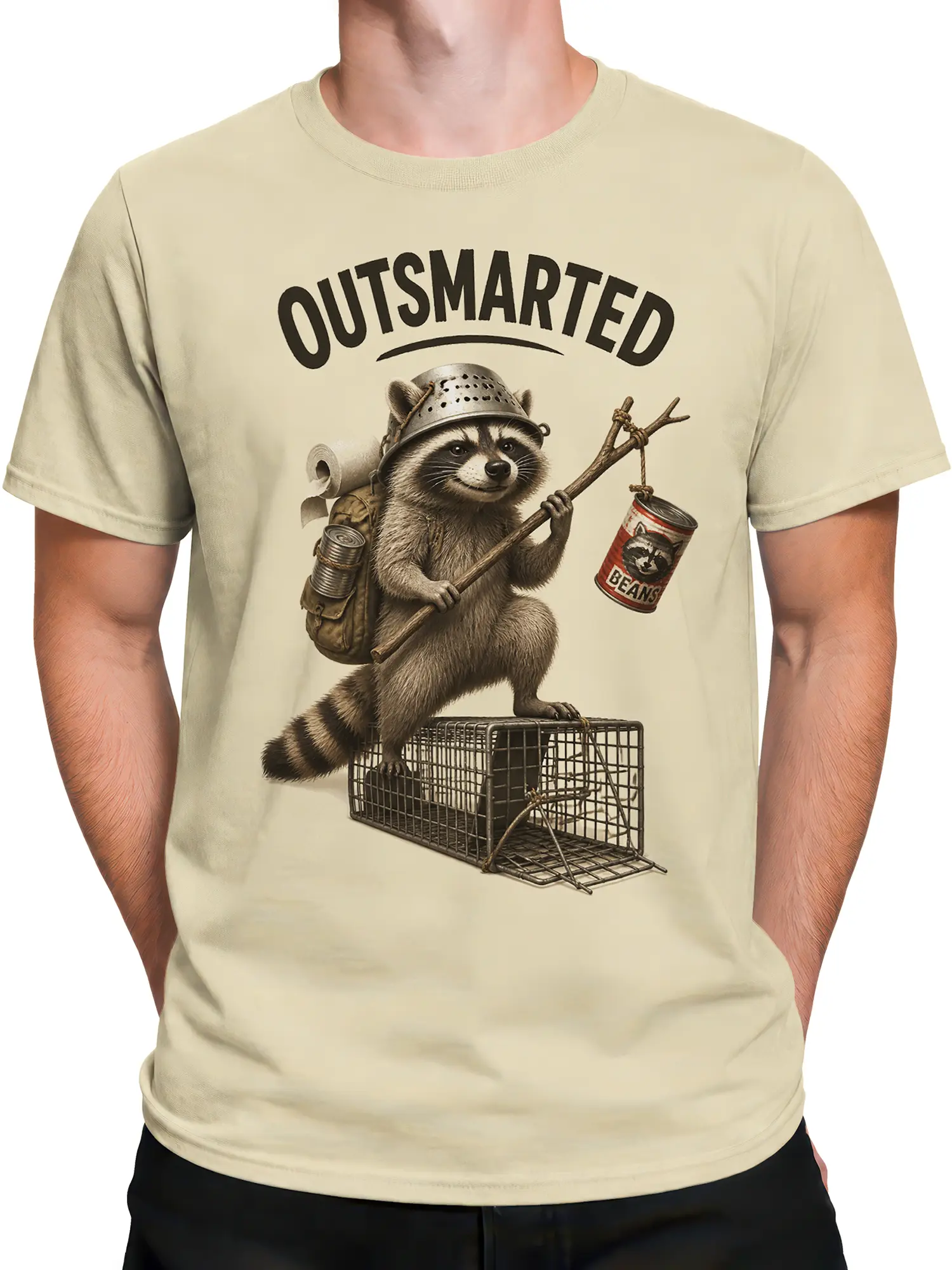 Male torso wearing a beige raccoon T-shirt with a helmeted raccoon escaping an open wire trap