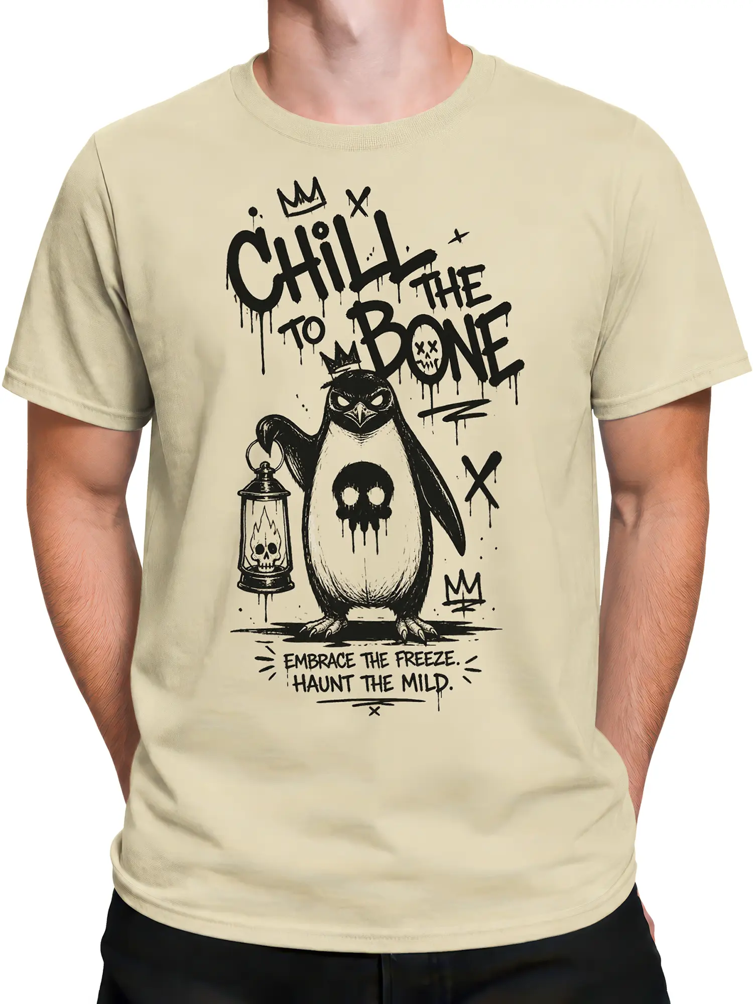 Male torso wearing a beige crowned penguin T-shirt with skull lantern and distressed winter-themed artwork