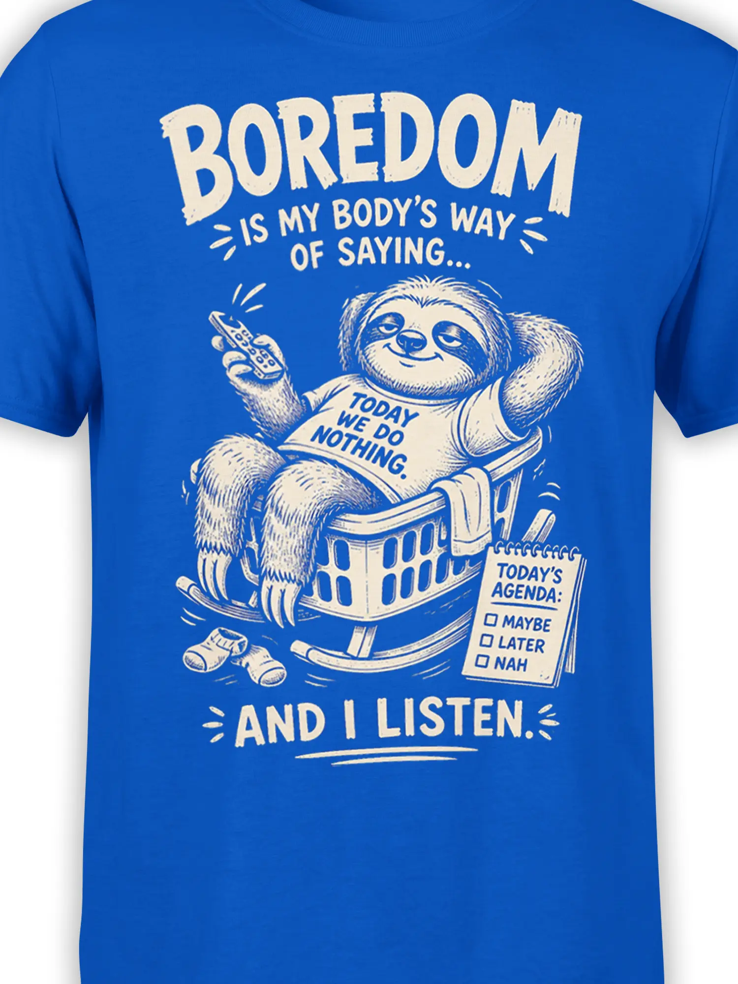 Close-up of sleepy sloth artwork, remote control, agenda, and cream lettering on a blue graphic tee