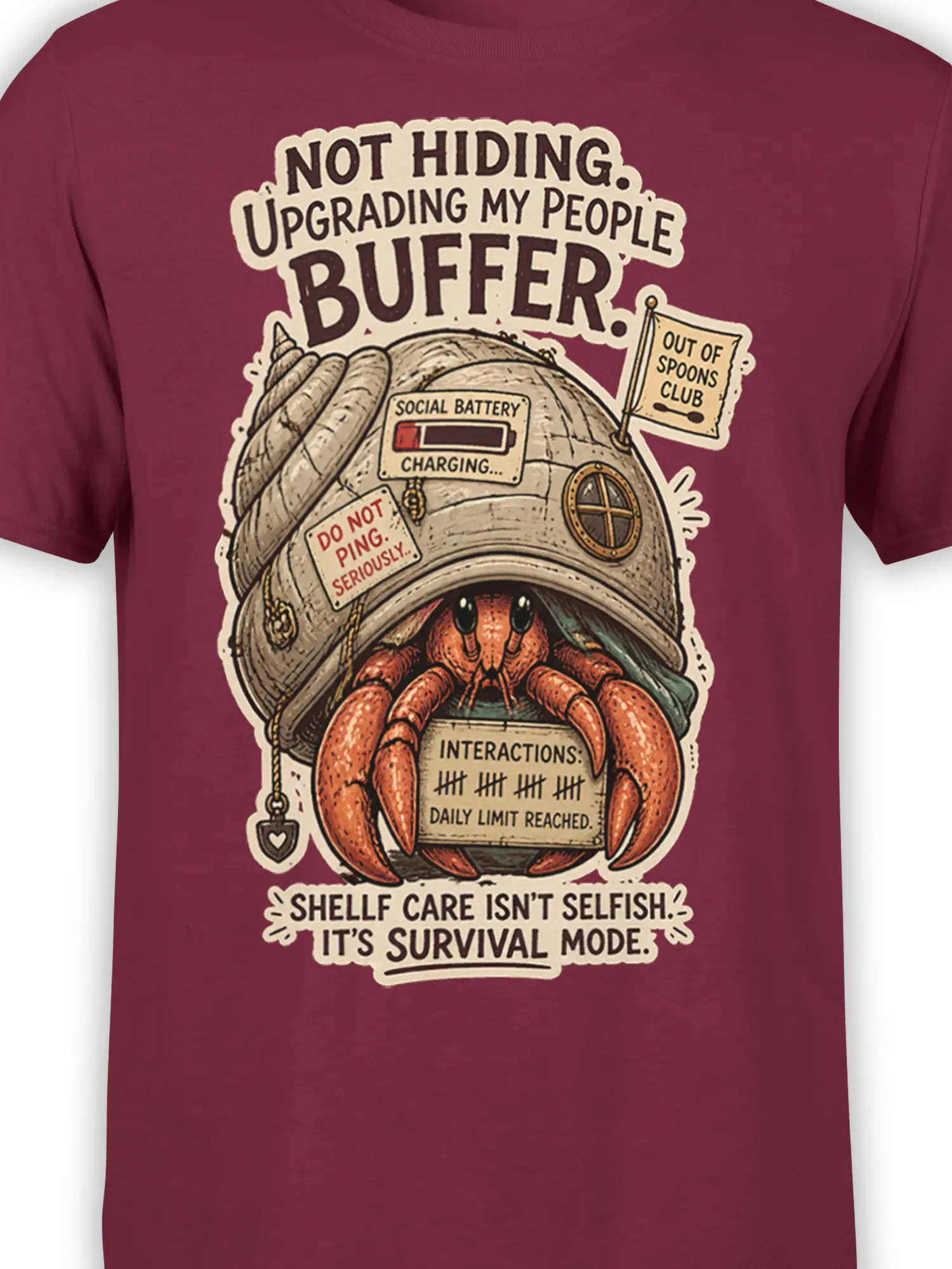 Close-up of a hermit crab shell graphic with introvert humor on a burgundy T-shirt