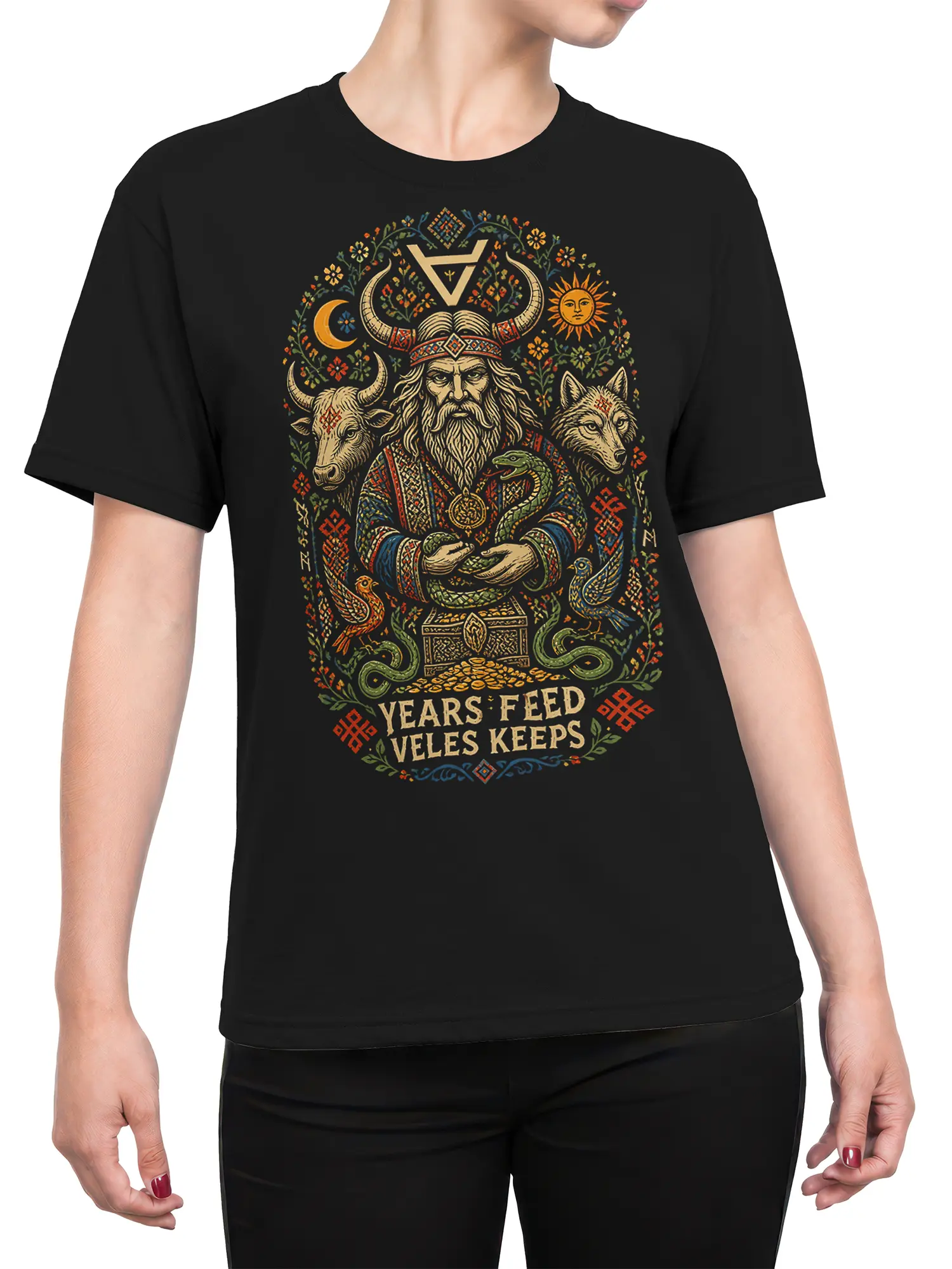 Female torso wearing a black mythology T-shirt with a horned figure, animals, celestial symbols, and folk-inspired artwork