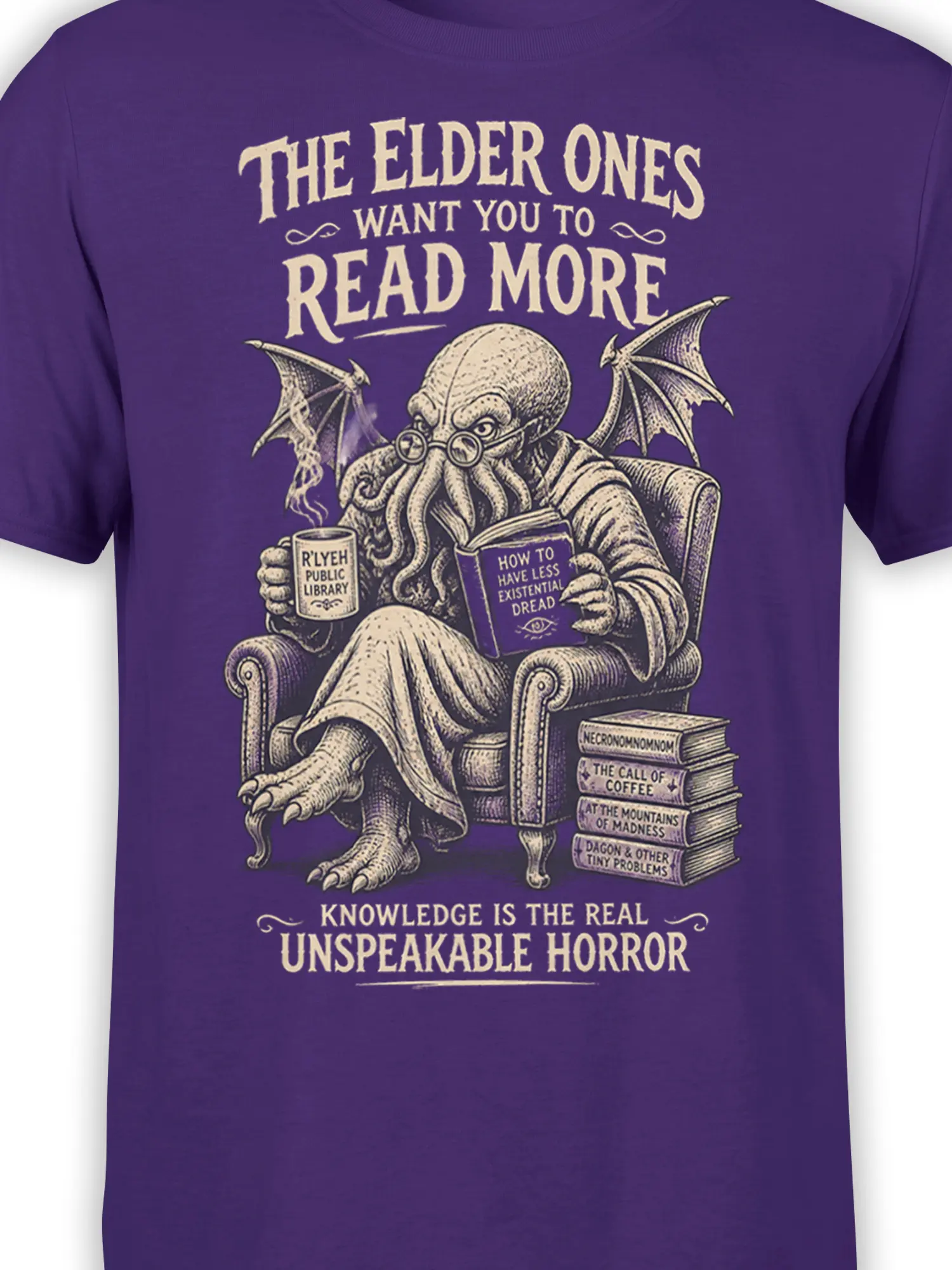 Close-up of the eldritch octopus, coffee mug, open book, and cream lettering on a purple shirt