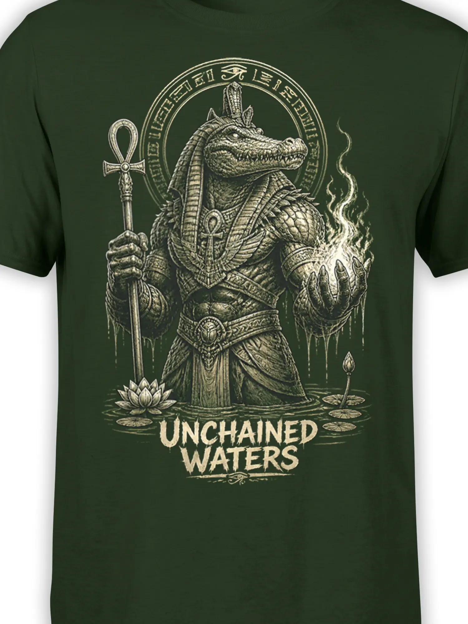 Close-up of armored crocodile artwork with ankh symbols and Unchained Waters text on a green T-shirt