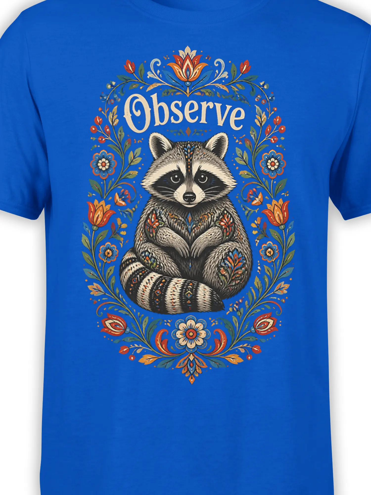 Close-up of the raccoon and “Observe” artwork with colorful flowers on a blue T-shirt
