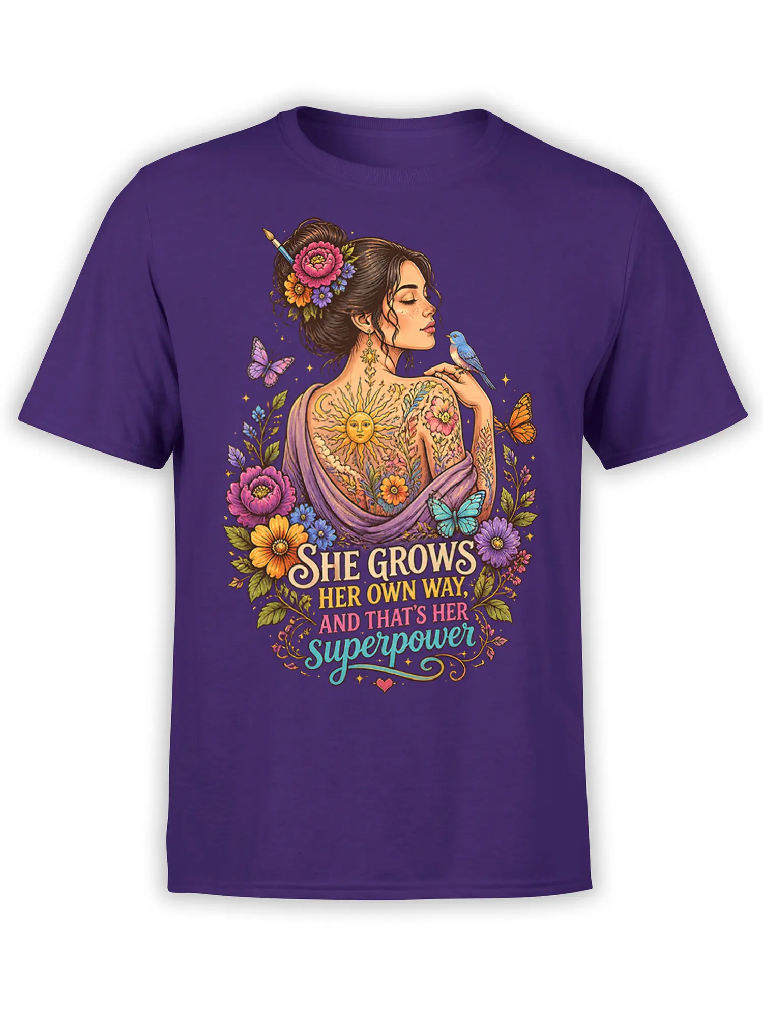 Purple T-shirt with a floral woman portrait, butterflies, blue bird, sun, and “She Grows Her Own Way” lettering