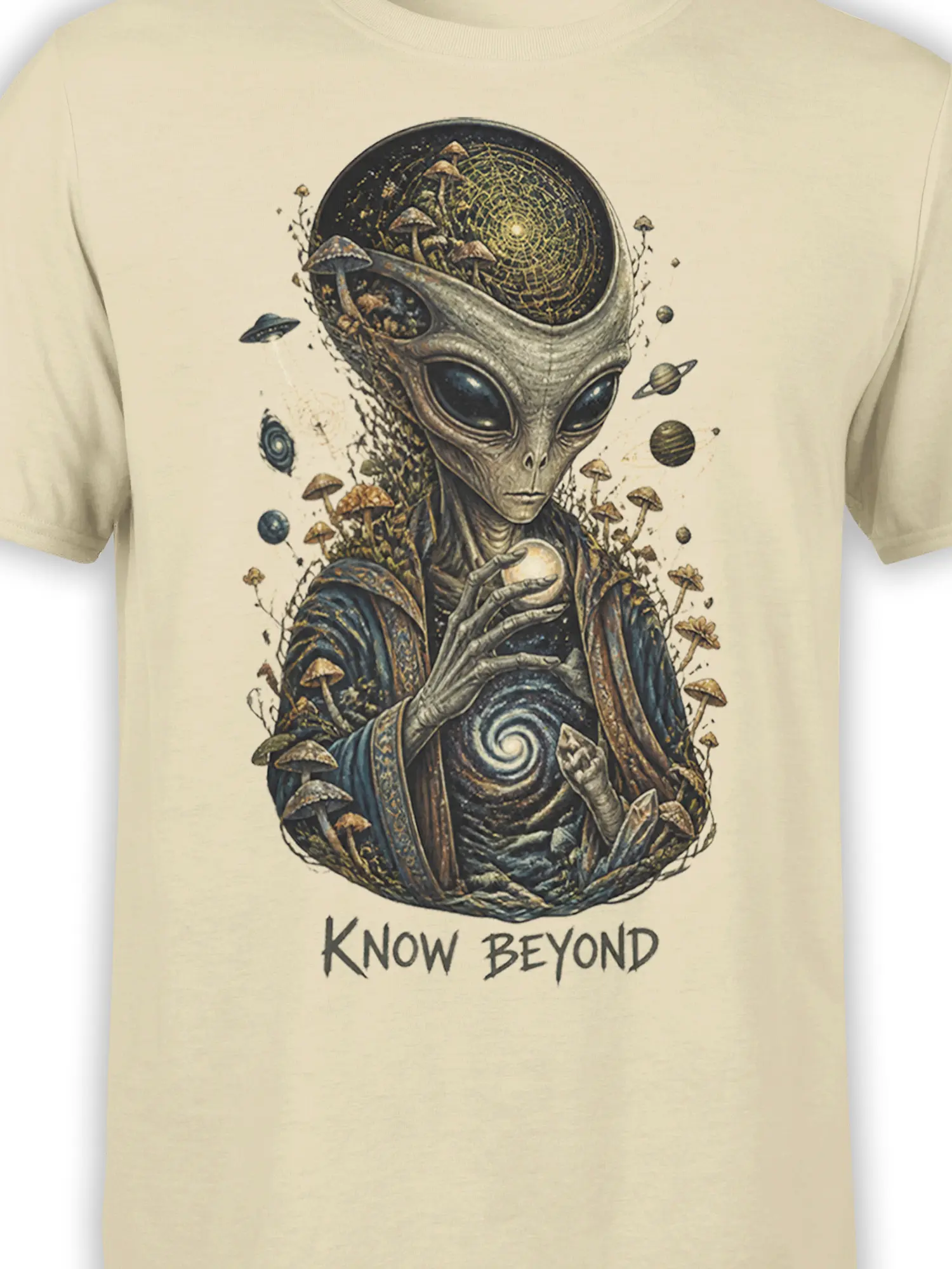 Close-up of the beige shirt design showing the alien face, mushrooms, planets, glowing orb, and cosmic details