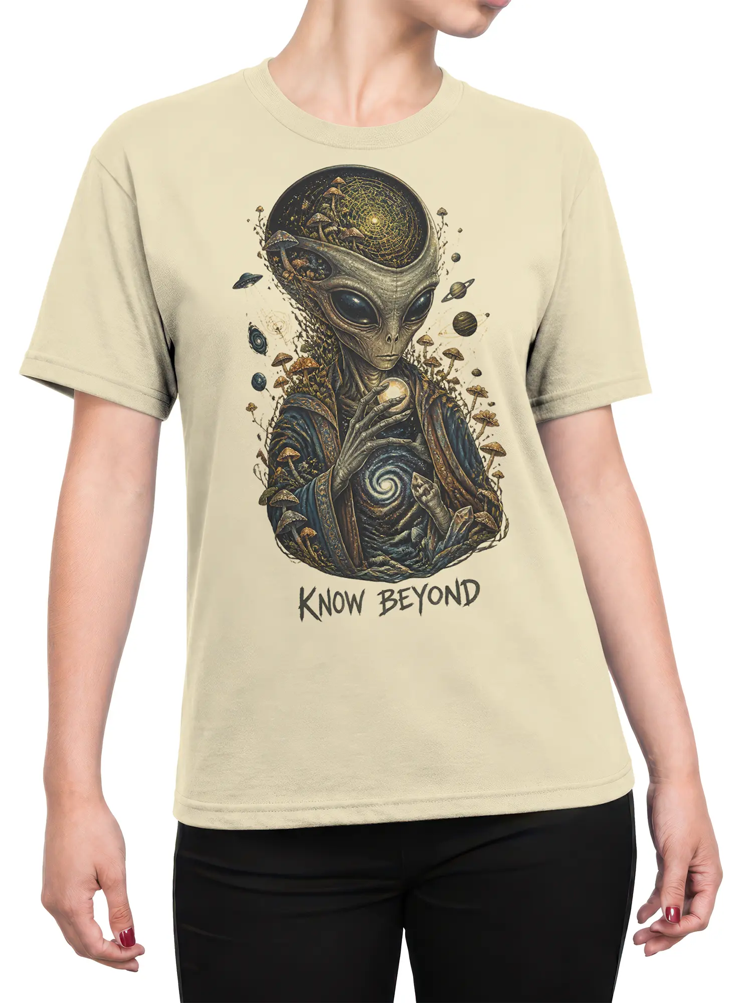Female torso wearing a beige alien graphic tee with mushrooms, planets, cosmic symbols, and Know Beyond lettering
