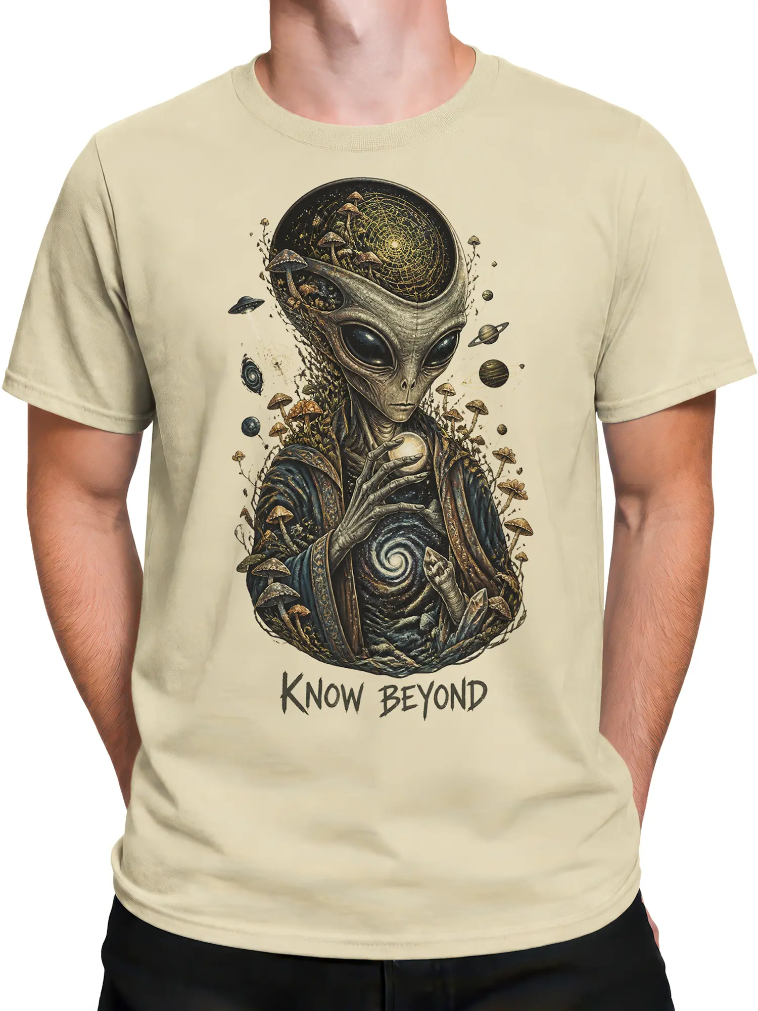 Male torso wearing a beige alien graphic tee with a mushroom forest, planets, cosmic symbols, and bold lettering