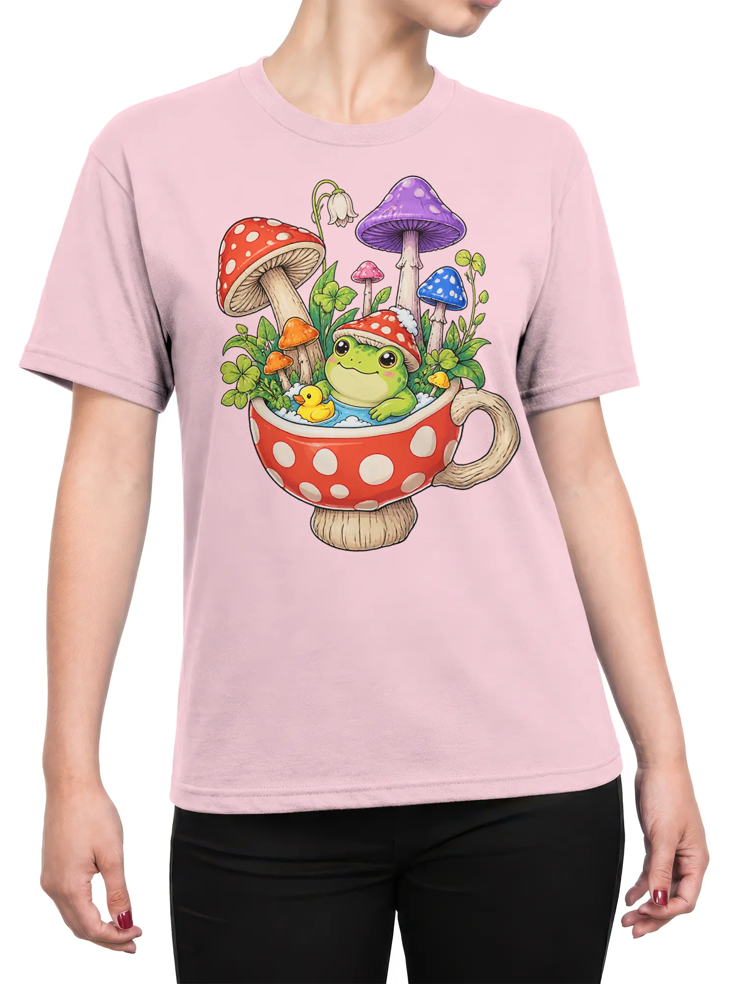 Female torso wearing a pink frog graphic tee with mushrooms, clovers, and a whimsical teacup design