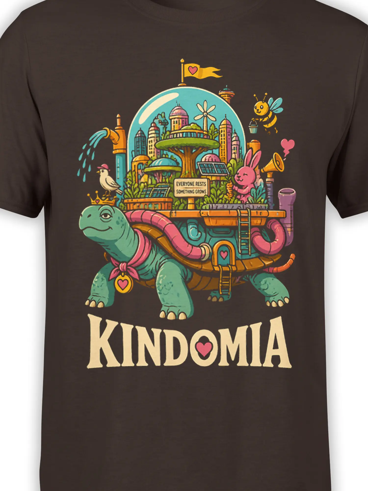 Close-up of the colorful turtle city graphic, animals, heart details, and KINDOMIA text on a brown shirt