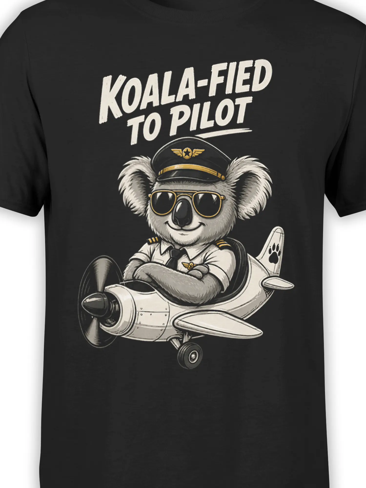 Close-up of koala pilot artwork on a black shirt with sunglasses, flight cap, airplane details, and cream text