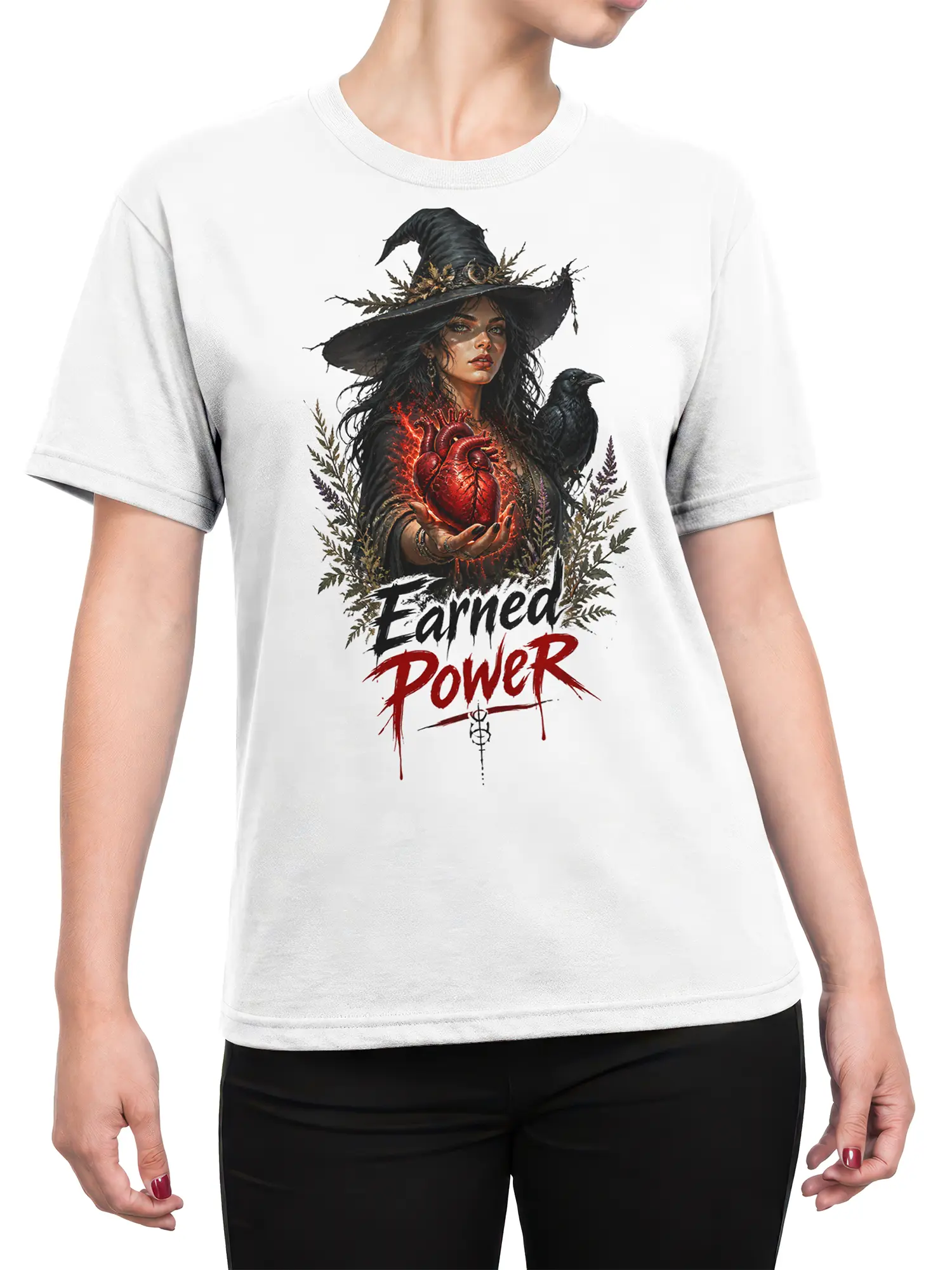 Female torso wearing a white witch T-shirt with raven, glowing heart, and “Earned Power” artwork