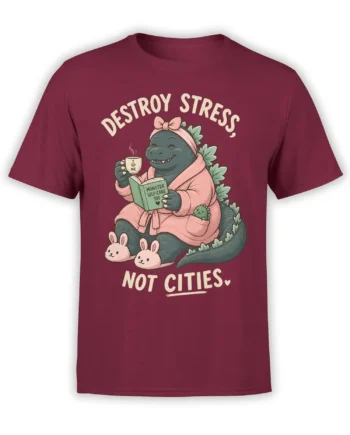 Cozy monster self-care graphic on a burgundy shirt with bunny slippers, pink robe, mug, and book