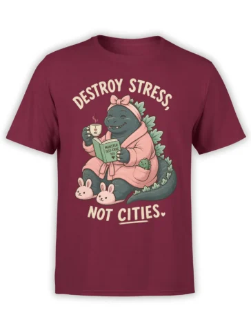 Cozy monster self-care graphic on a burgundy shirt with bunny slippers, pink robe, mug, and book